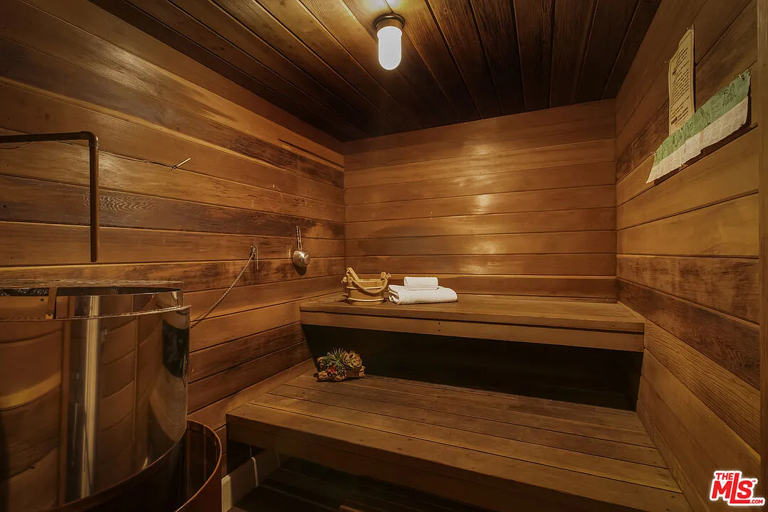 Finished entirely in wood, the sauna is designed as a compact, enclosed room with tiered bench seating.