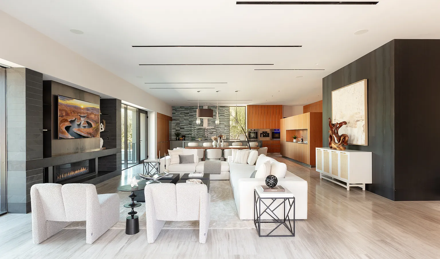 Neutral-toned sofas and textured accent chairs make up the space without breaking its flow, complemented by stone flooring that runs underfoot.