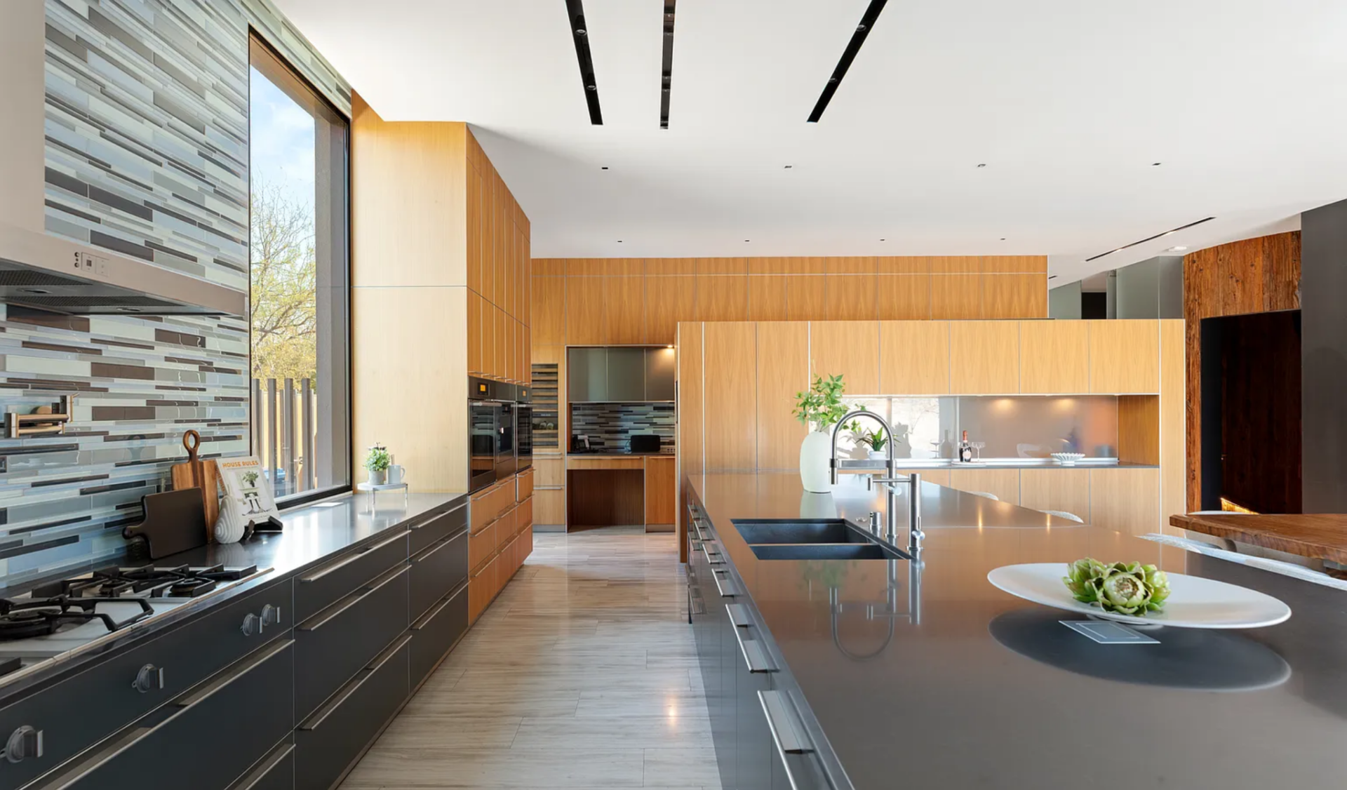 Top-tier appliances are built into the cabinetry, and a full-height backsplash adds texture behind the cooking area.