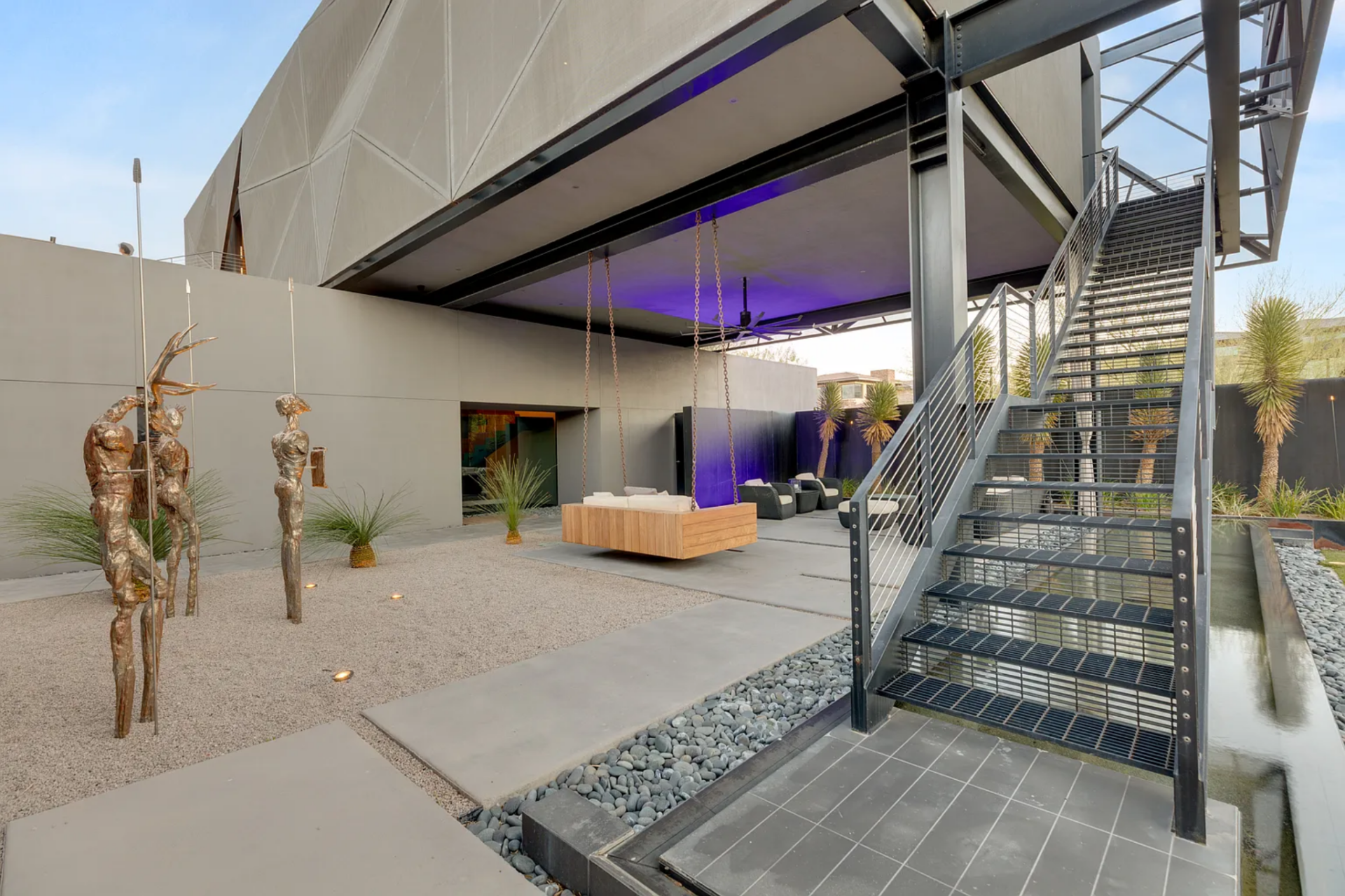 From here, a steel staircase rises along the edge, creating a clear transition point that connects up to the bedrooms and continues toward the backyard.