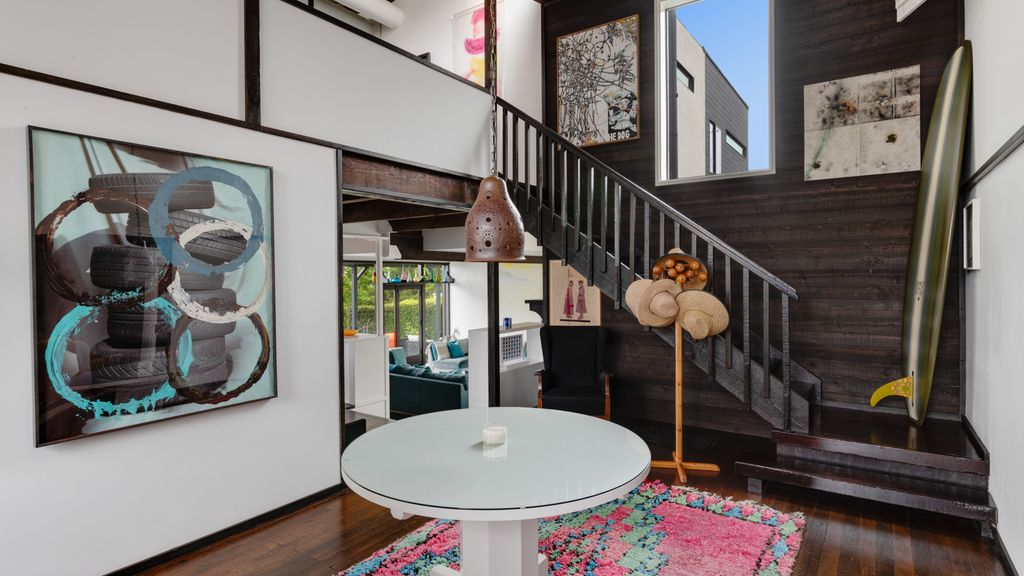 A round table sits in the center, while the staircase rises along a paneled wall lined with artwork giving the foyer a collected feel before the main living spaces begin.