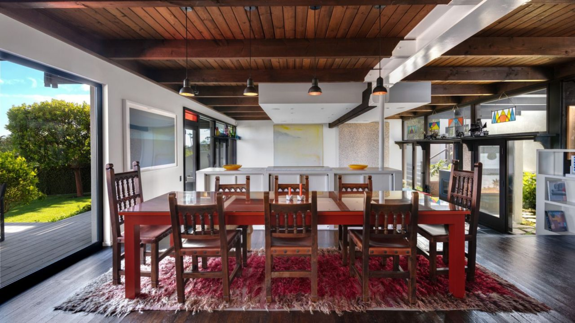 Stepping back up from the living room, the dining area consists of a long wood table that sits beneath a series of pendant lights.