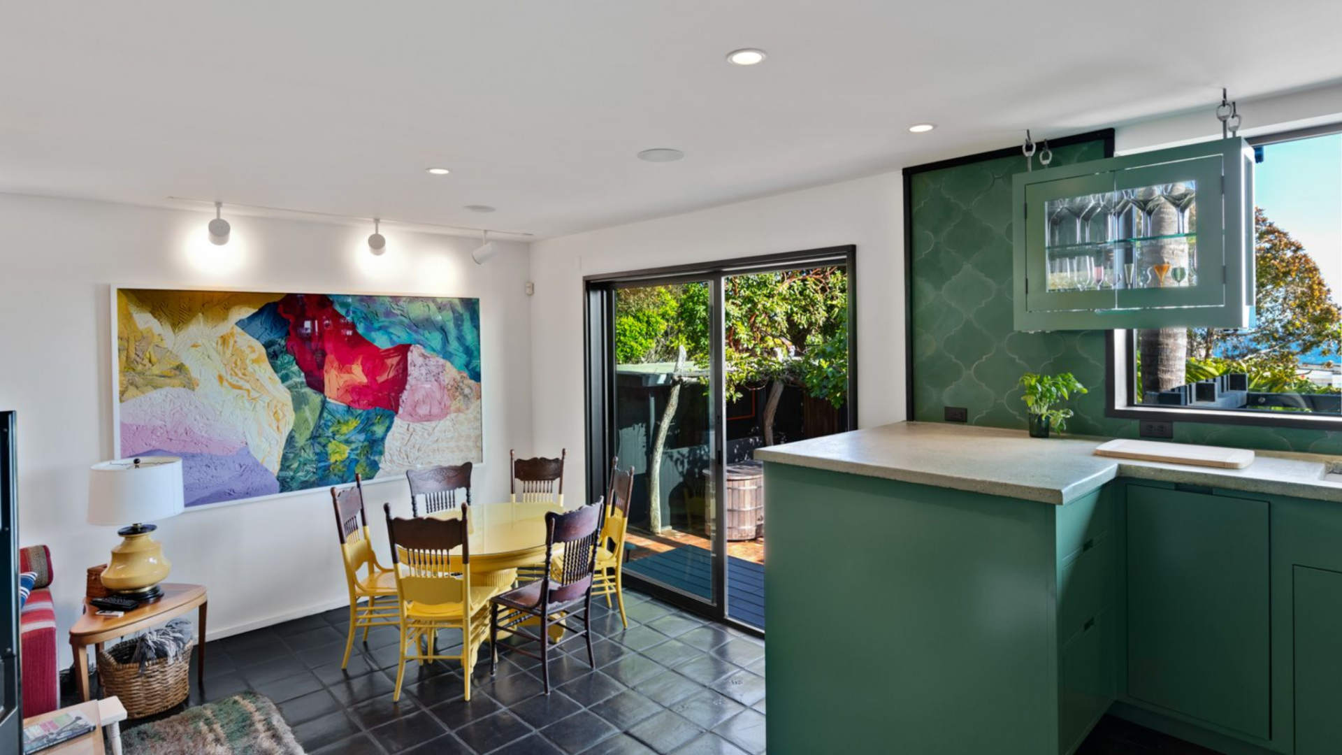 Set beneath exposed wood beams and lined with windows on one side, the kitchen maintains a strong connection to the outdoors alongside a small breakfast nook.