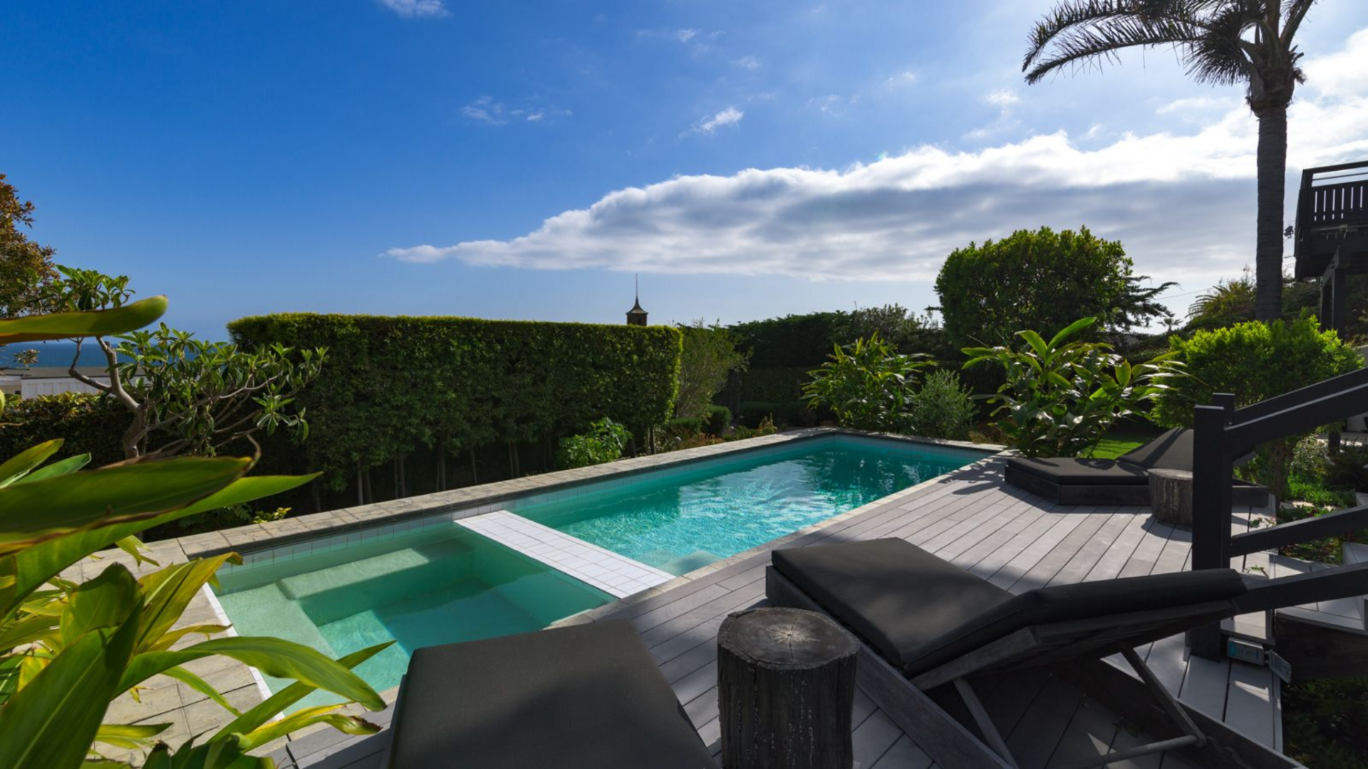 Just below the deck, a rectangular pool is paired with a raised spa at one end, separated by a clean tiled edge that defines the two zones.