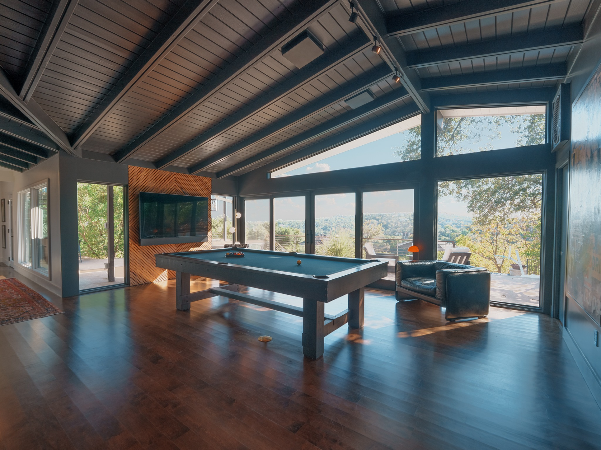 In the billiards room, vaulted ceilings soar above wide-plank wood floors and a central pool table positioned to take full advantage of the view. 