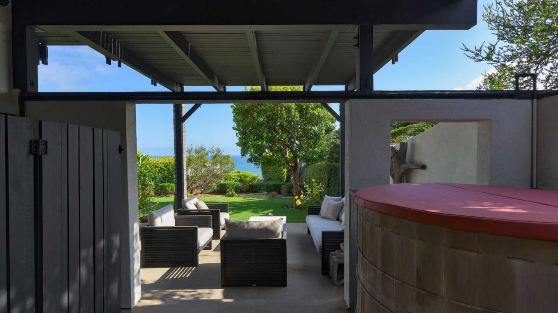 Tucked beneath the upper deck, the hot tub sits within a more sheltered patio space, partially enclosed by the structure above.