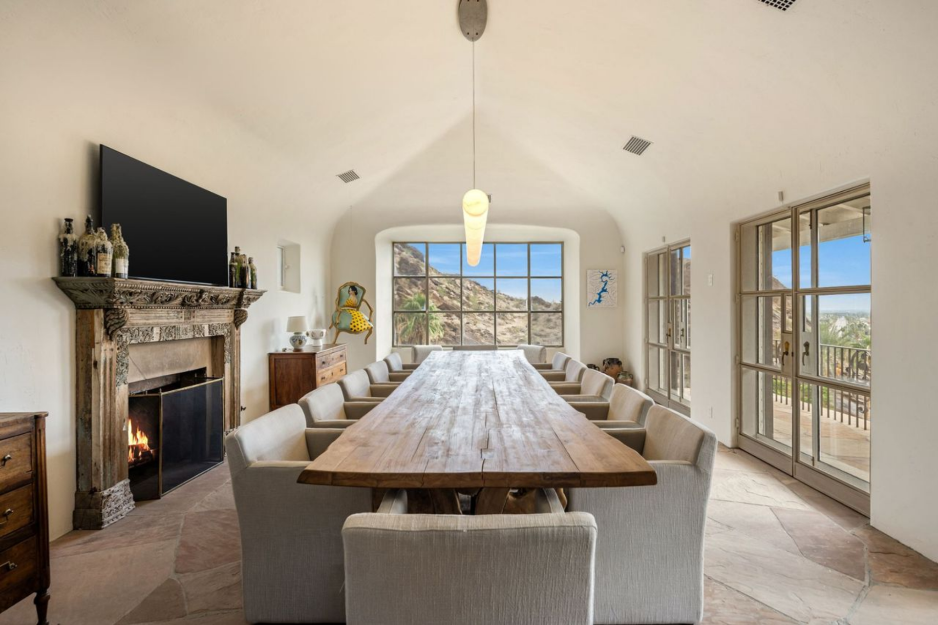 The formal dining room features a long wood dining table that runs the length of the room, surrounded by upholstered chairs.