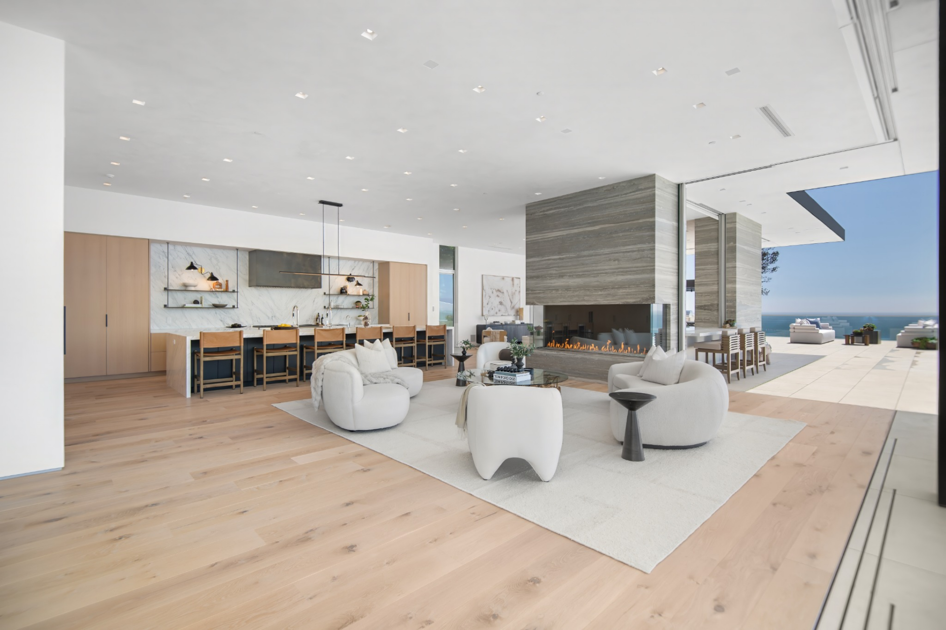 At the center is the living room, set around a bold bay fireplace wrapped in stone, which helps divide the room without closing it off.