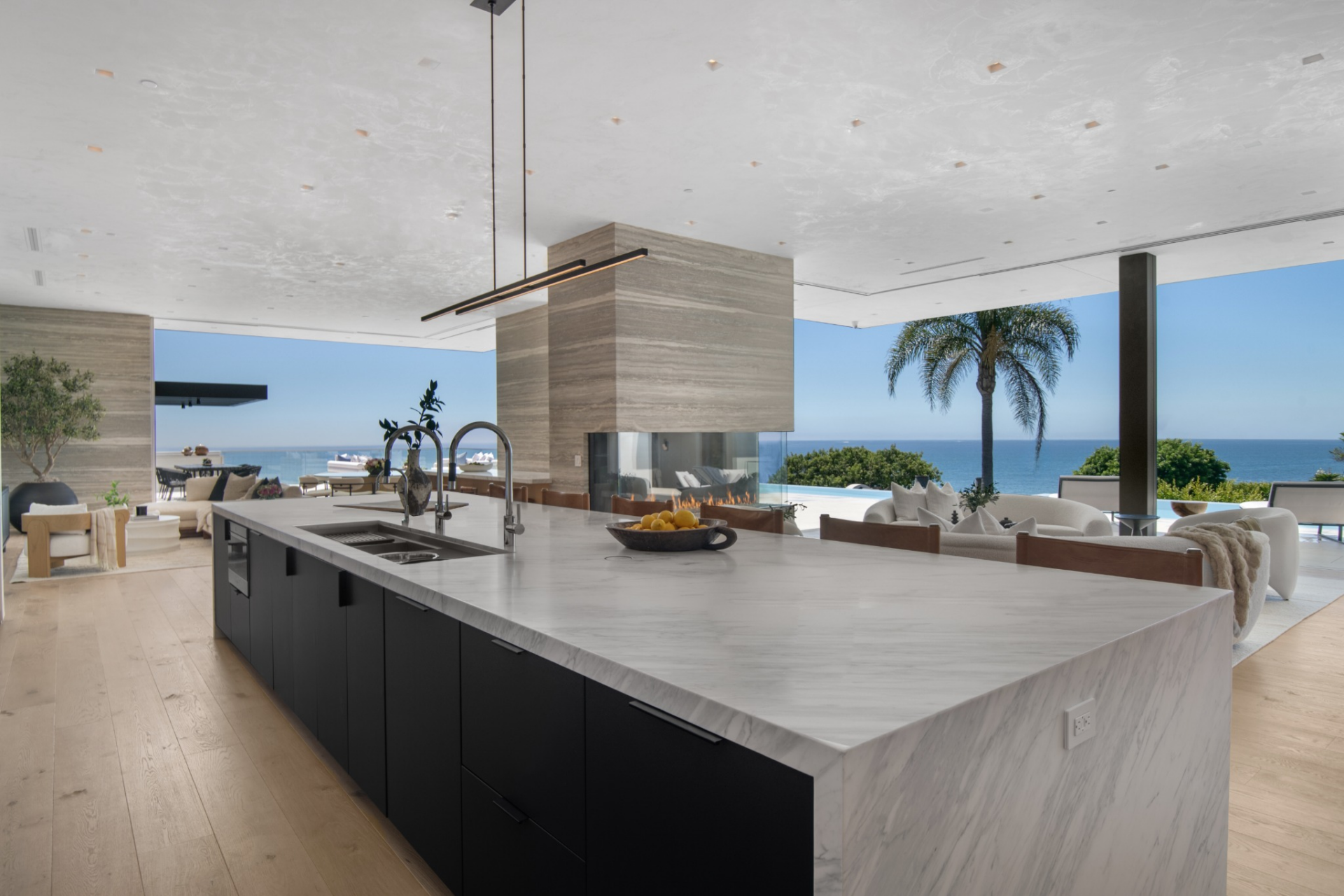 Wrapped in waterfall stone with dark cabinetry below, it includes an integrated sink, seating along one side, and enough surface area to work as both prep space and gathering spot.