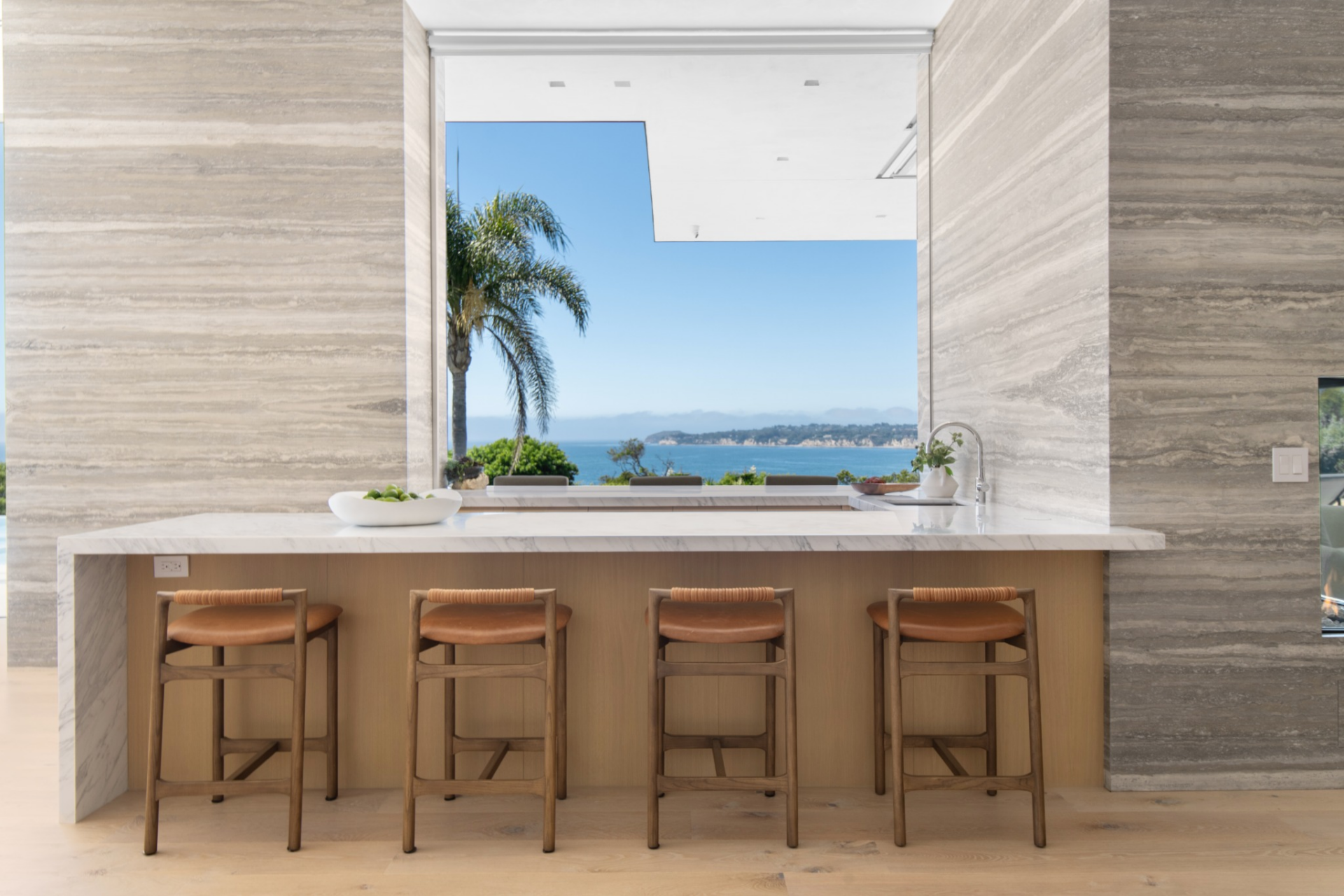 Inside, the bar is set into the opening between two stone walls, with four stools tucked beneath a marble counter that faces straight out toward the water.
