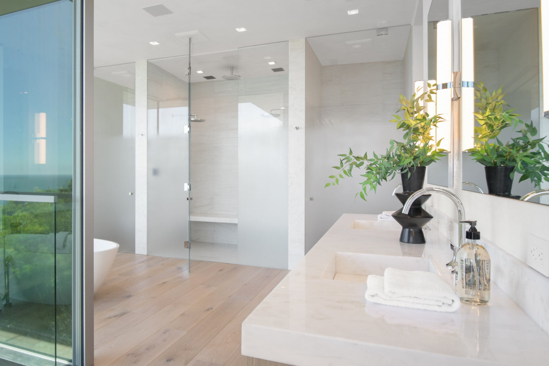 From there, the suite opens directly into the bathroom, where a long dual vanity runs along one wall beneath large mirrors and integrated lighting.