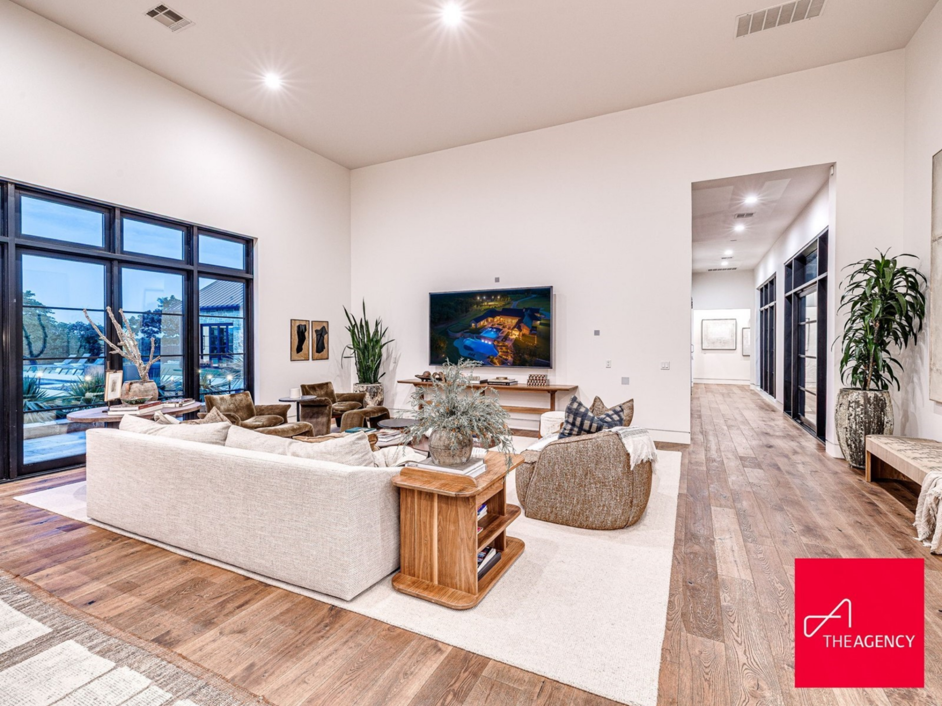 Closest to the front door, the media lounge is arranged around a large sectional on top of a neutral rug, creating a relaxed gathering area in front of the TV.