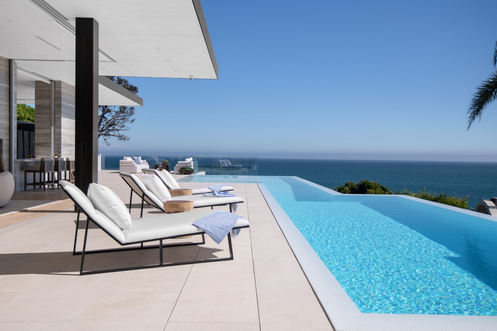 Set along the edge of the terrace, the zero-edge pool runs parallel to the ocean view and is surrounded by wide stone decking.