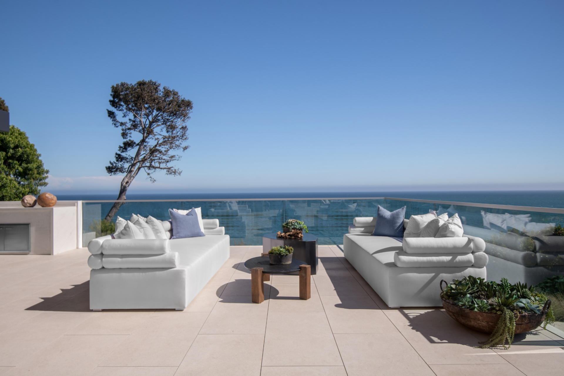 Two low-profile sofas face one another across a cluster of tables, creating a simple sitting area that stays open to the water.