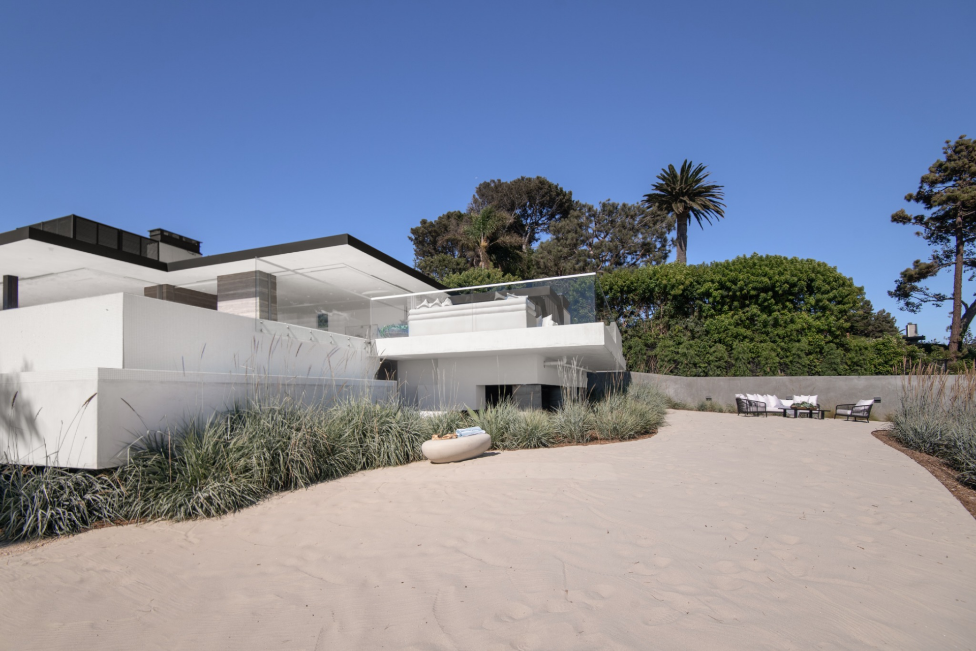 Below the main terrace, the property opens to a private sand area that adds another outdoor zone closer to the bluff’s edge.
