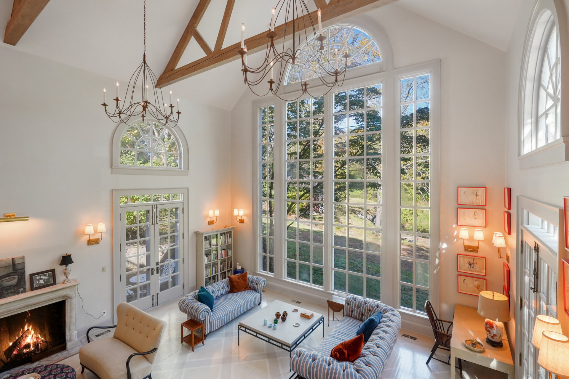 Below, the 30-foot tall ceilings are softened by curved seating, pale floors, and French doors that open directly to the grounds, keeping the connection to the landscape present from the moment you step inside.