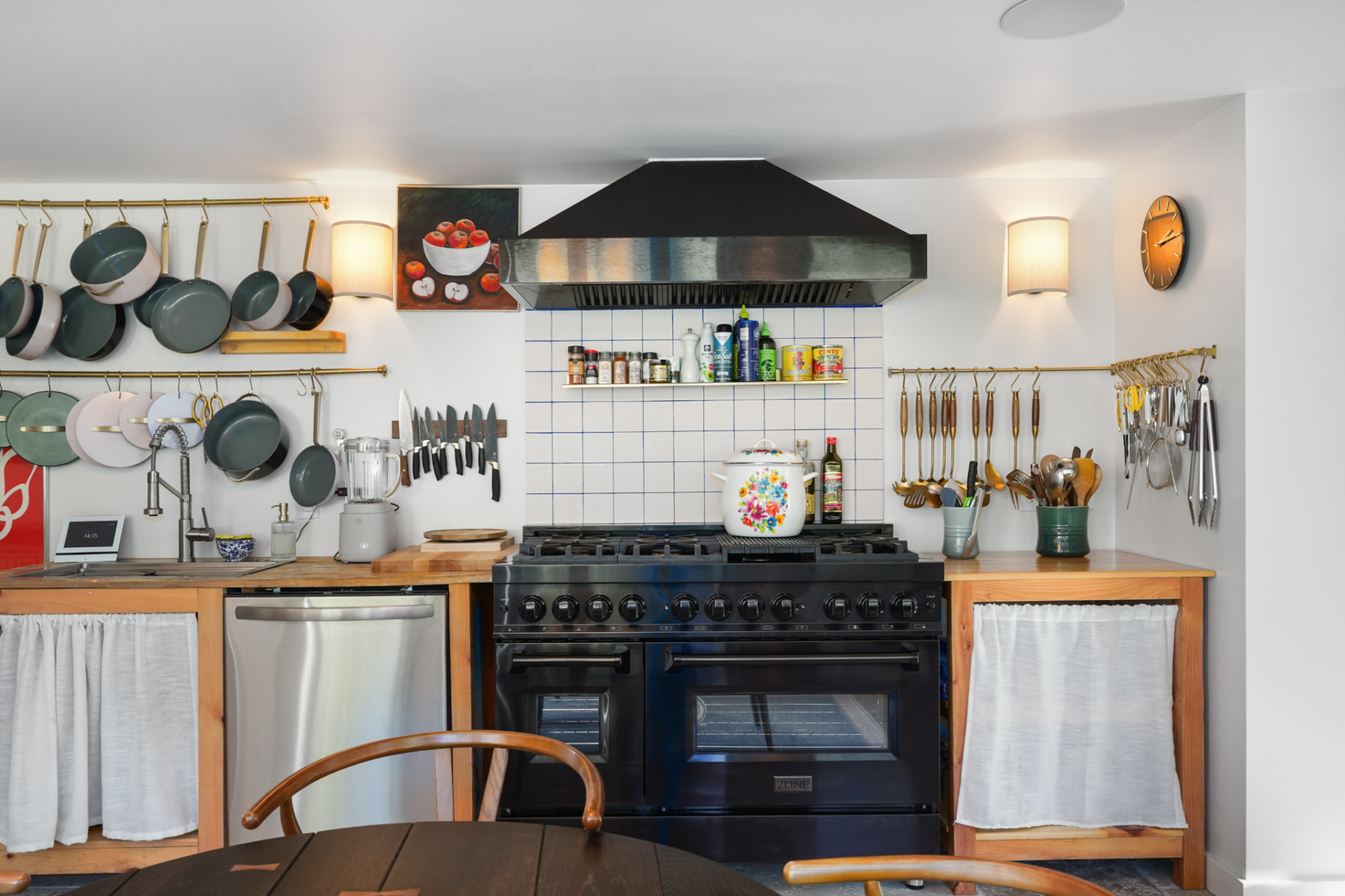 A wide black range sits between walls lined with hanging pots, pans, and cooking instruments.