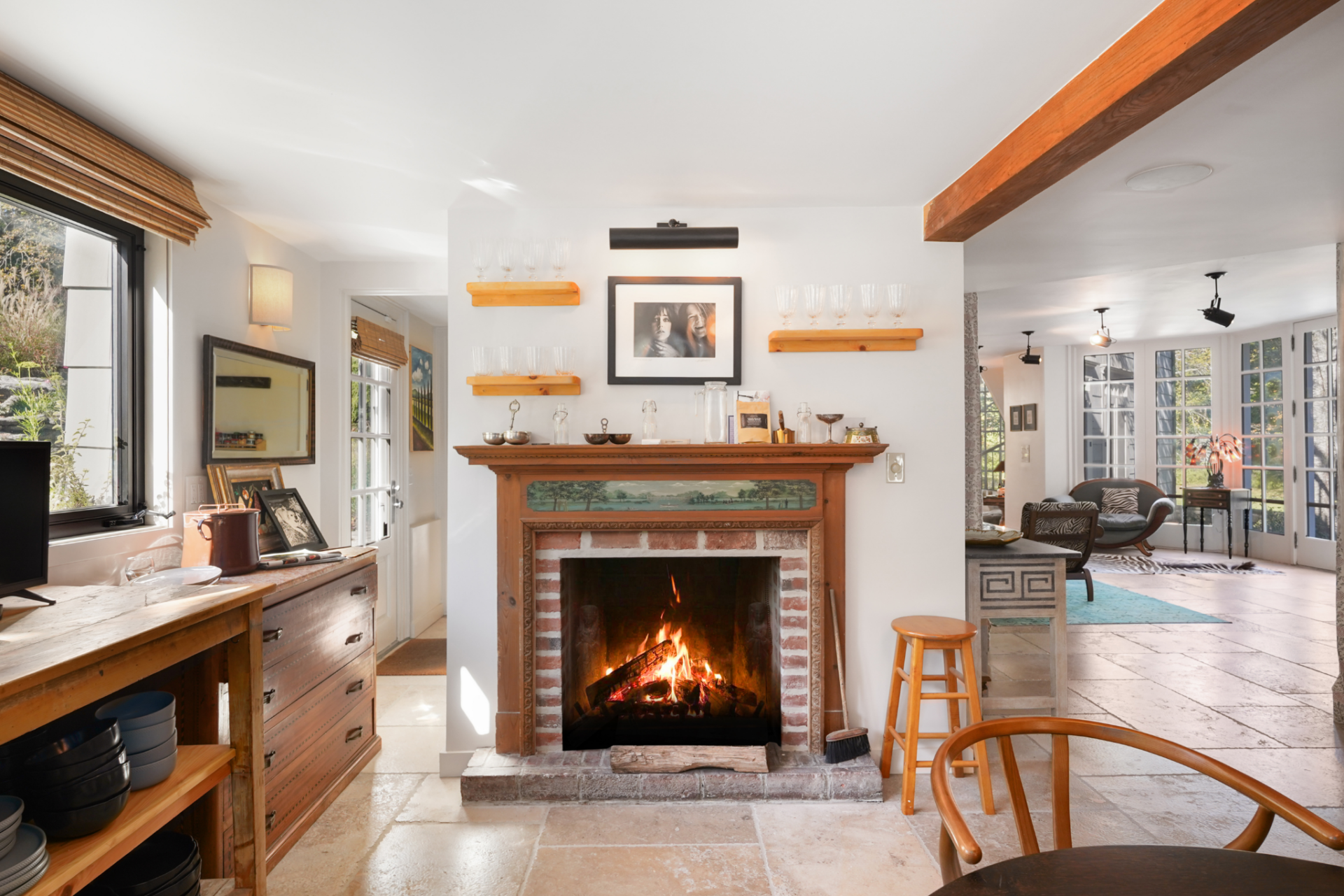 Another fireplace topped with a mix of different cooking tools adds even more warmth to the room and helps connect the kitchen back to the connected living areas.