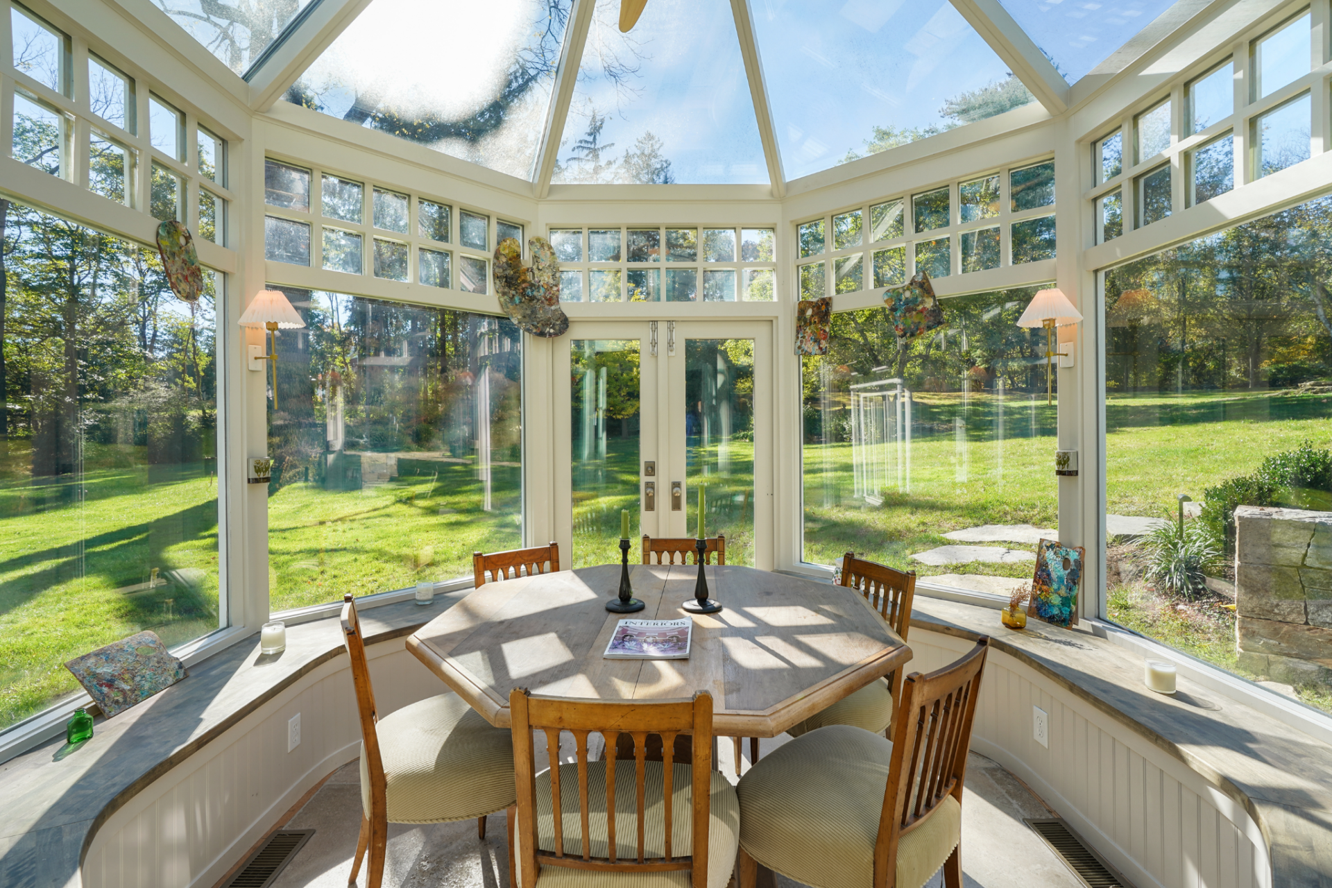 A round table sits at the center, surrounded by wraparound windows that lead up to a pitched skylight overhead, pulling in light from nearly every direction.