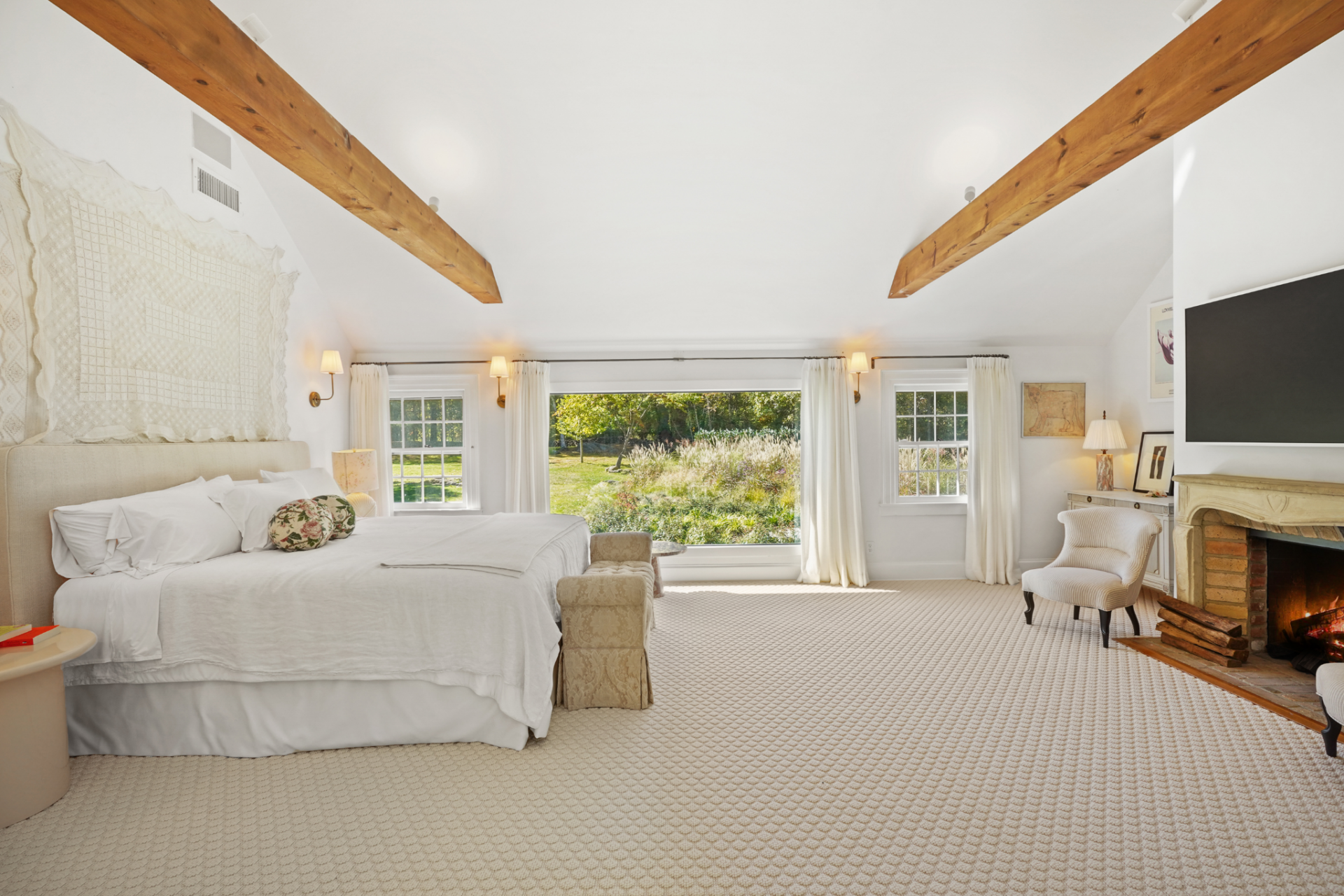 A limestone fireplace and wall-mounted television sit to one side, while the rest of the space is left largely open, giving the room a calm, oversized layout rather than breaking it up with extra furniture.