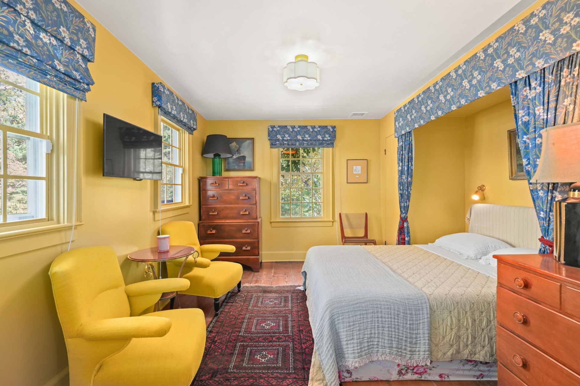 Another bedroom takes a much brighter approach, using mustard-yellow walls and blue floral fabric around the windows and bed alcove to give the room a more playful look. 
