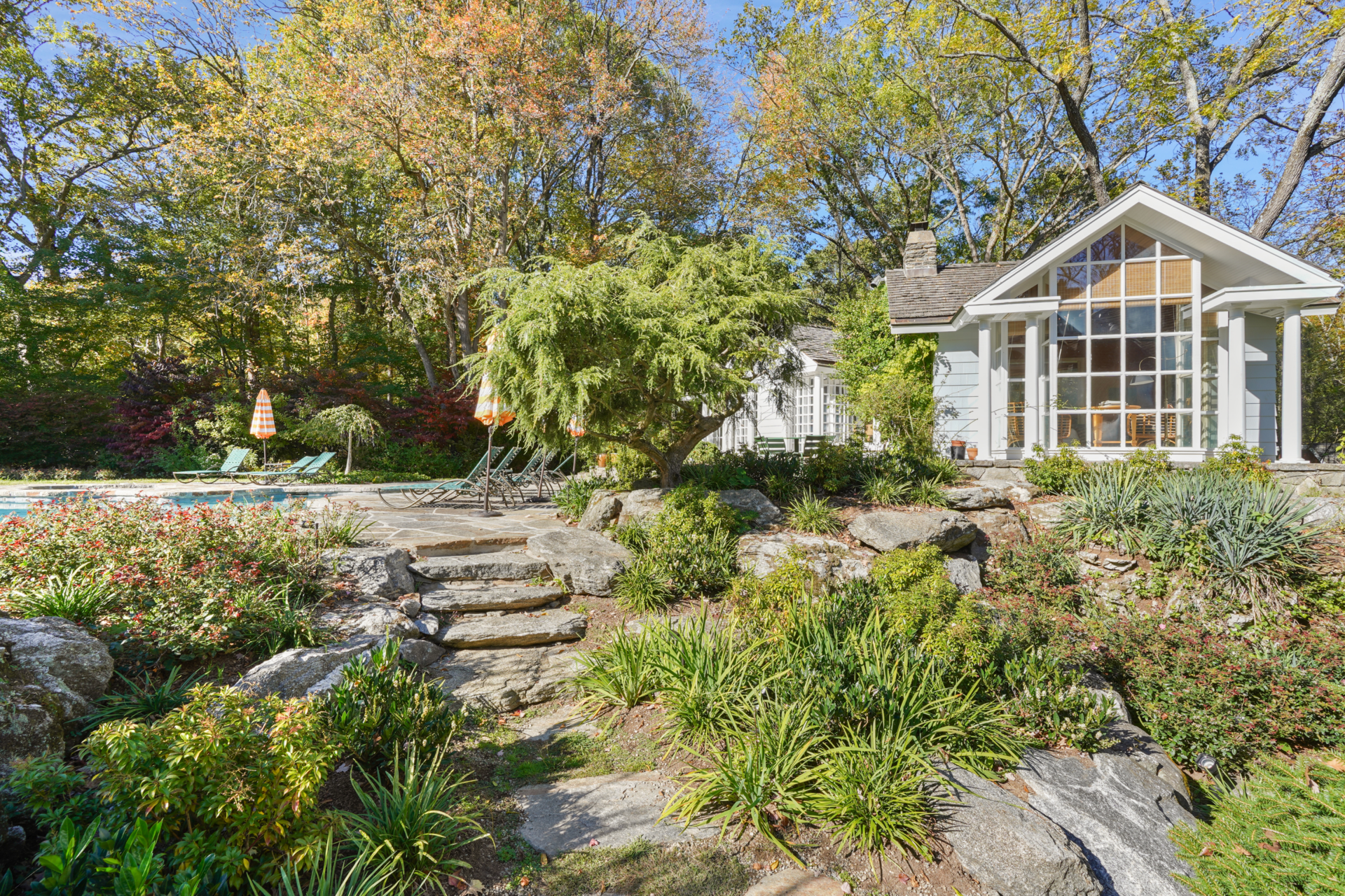 Only a few steps away from the main house, the pool house is fully furnished, with vaulted wood ceilings, garden-facing windows, and a warmer palette than the main house.