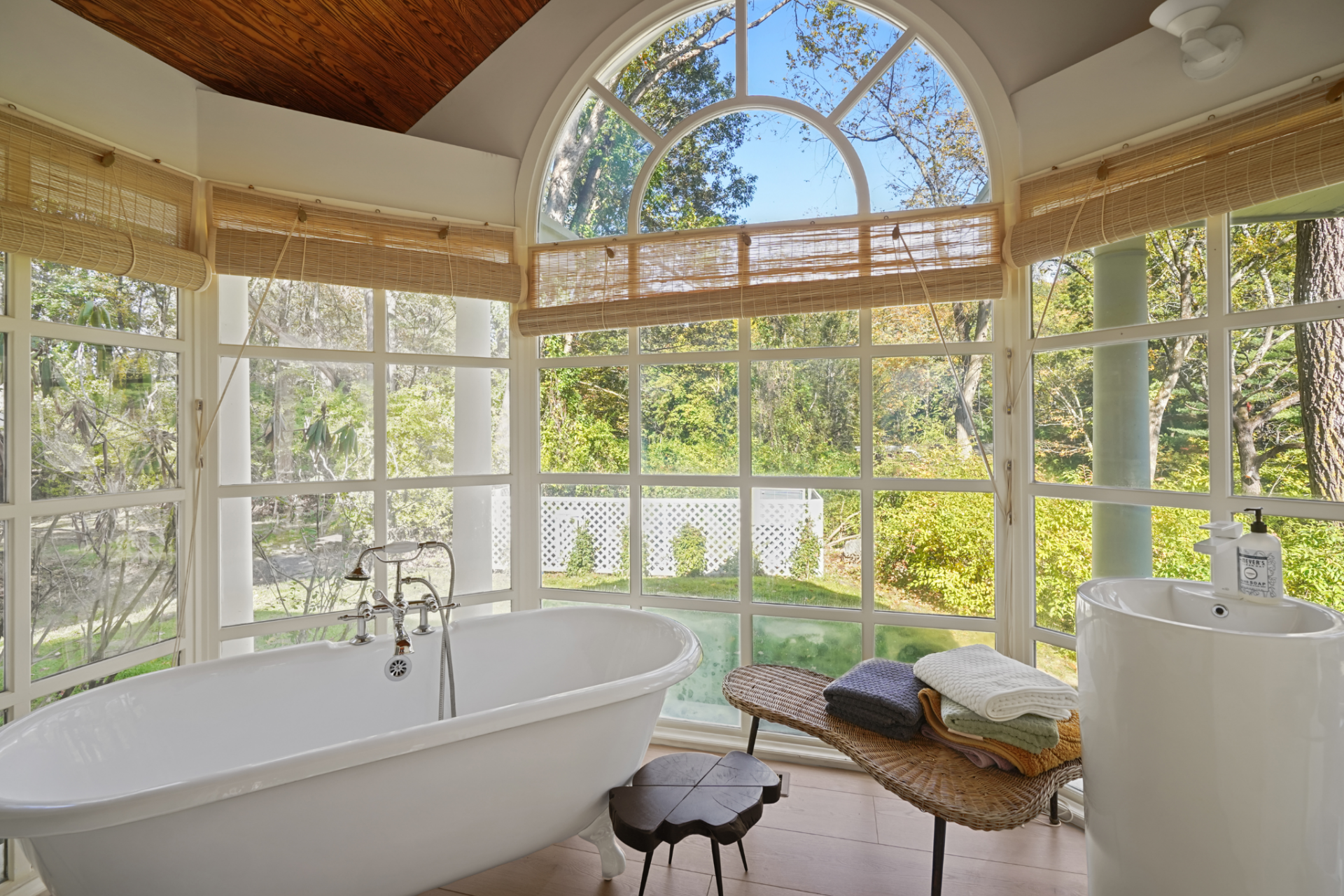Lastly, the bathroom has a freestanding tub placed directly in front of a wall of windows beneath a large arched transom. 