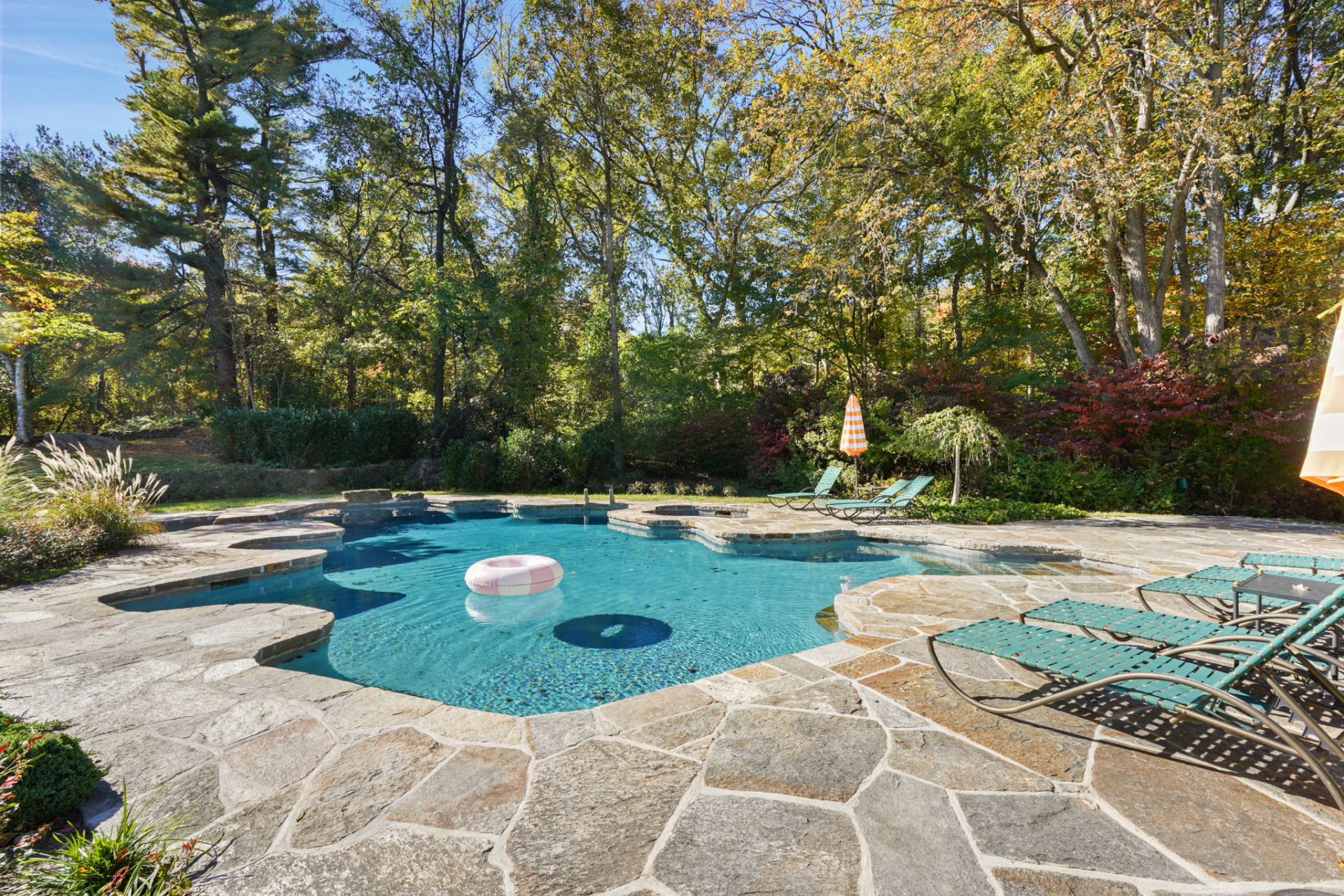 The pool area is set within a broad stone surround and shaped with softer, irregular edges that feel more in line with the natural setting around it. 