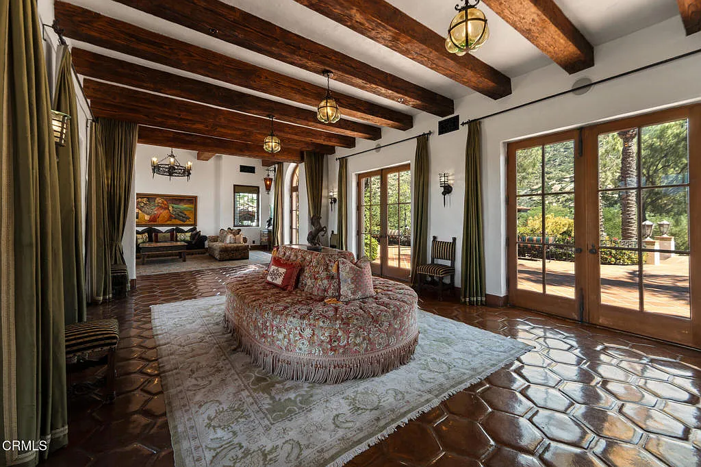 This hallway lounge has a round upholstered settee on top of an area rug, turning the corridor into a small seating zone rather than leaving it as a pass-through space.