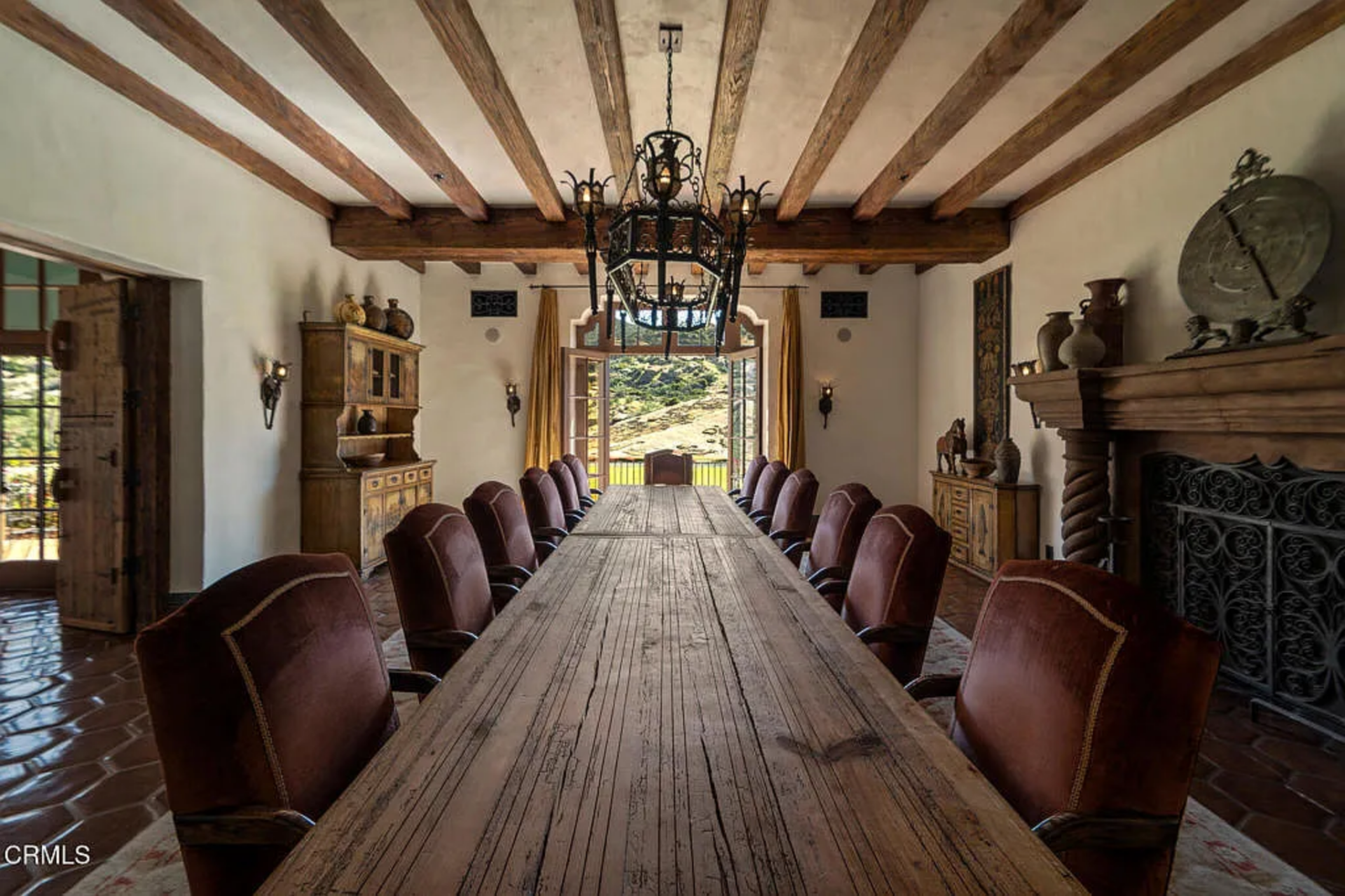 The formal dining room is also scaled for large gatherings, with a long plank wood table running nearly the full length of the space and lined with high-back leather chairs on both sides. 