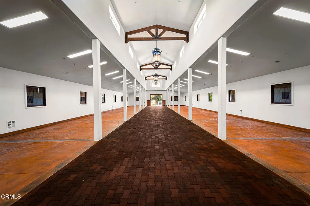 Inside, a long central aisle runs through the middle beneath a high vaulted ceiling, with exposed trusses, clerestory windows, and hanging lanterns bringing structure overhead. 