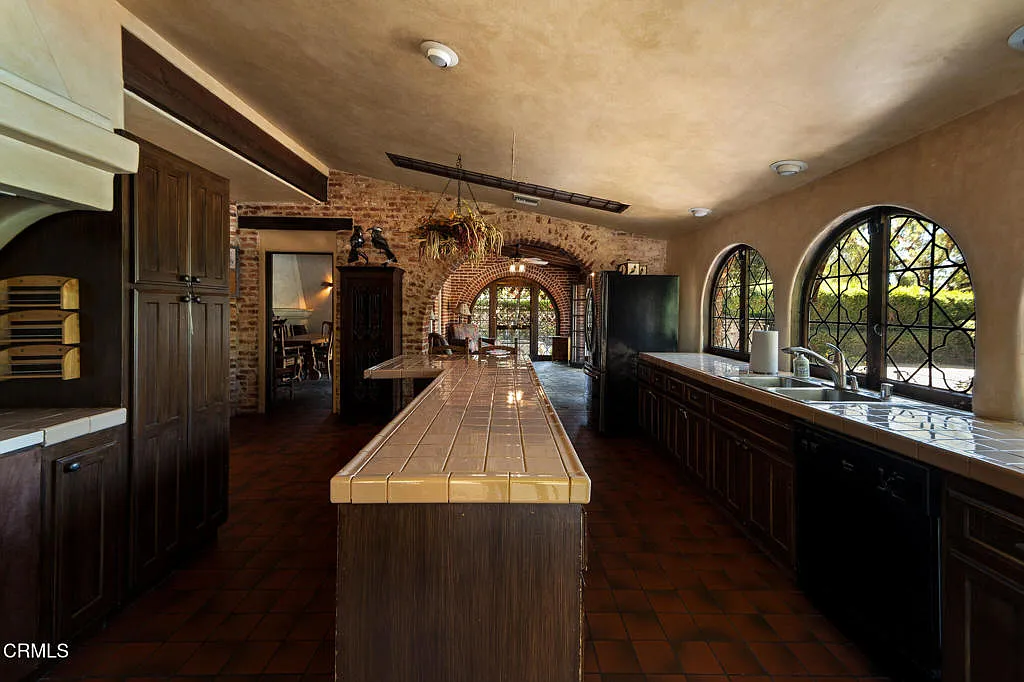 Inside, the kitchen is laid out as a long working space with a central island running through the middle and a full wall of counters and windows to one side. 