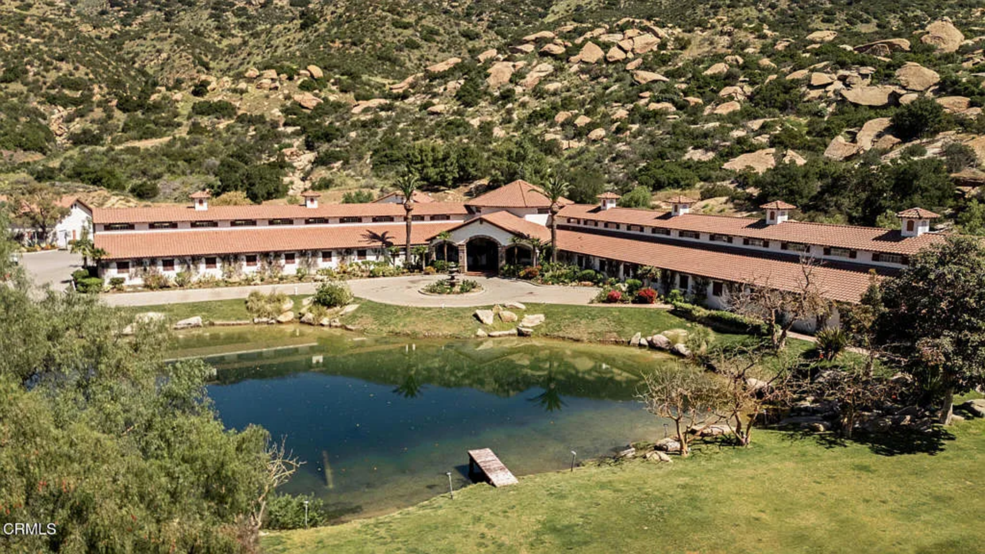 A private lake sits in front of one of the larger outbuildings, bringing a quieter and more reflective element to the ranch. 