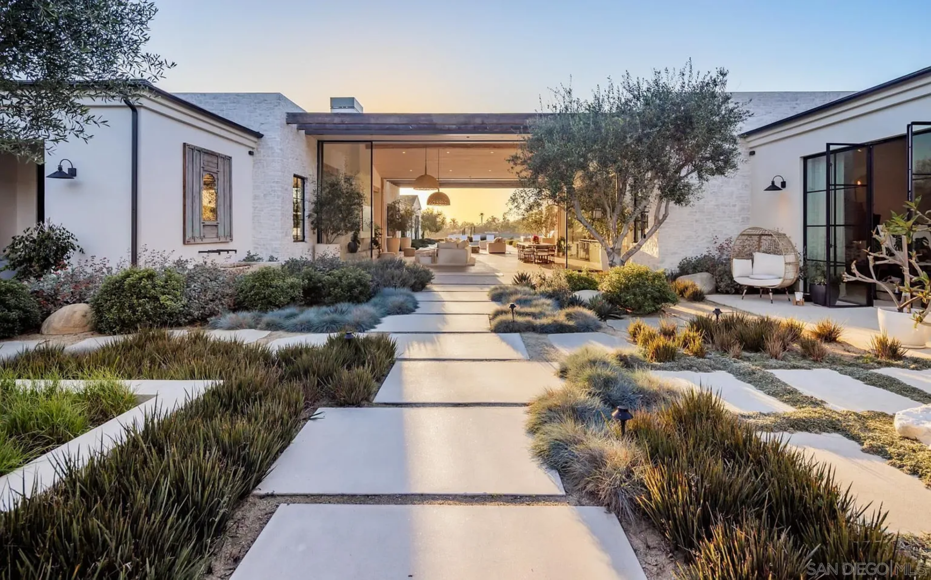 White masonry walls, black steel-framed openings, and warm wood accents give the entry a clean, modern look, while the long axis keeps your eye fixed straight ahead.