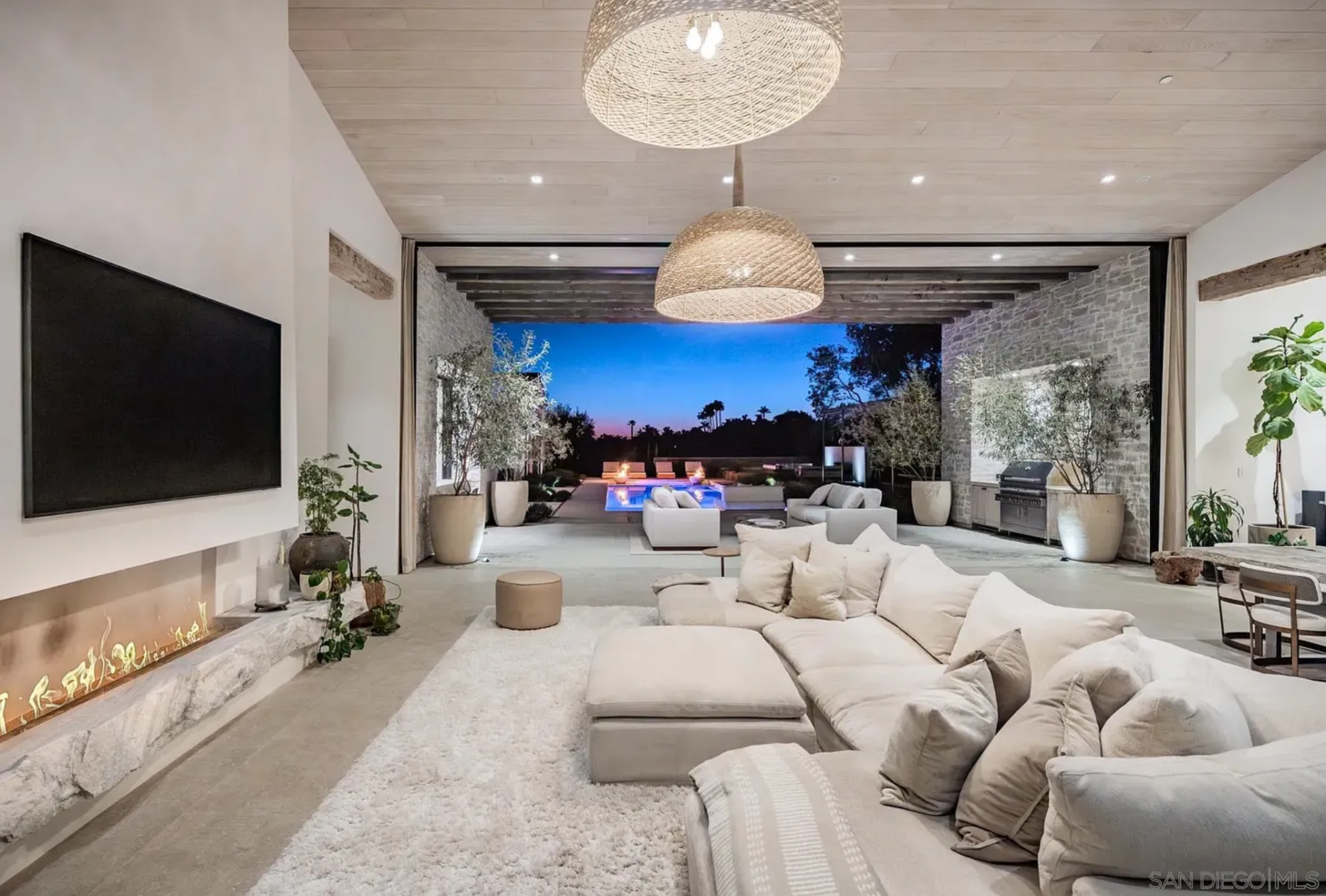 Inside the great room, the living area is arranged as a long, open space with low sectional seating set in front of a linear fireplace and mounted TV. 