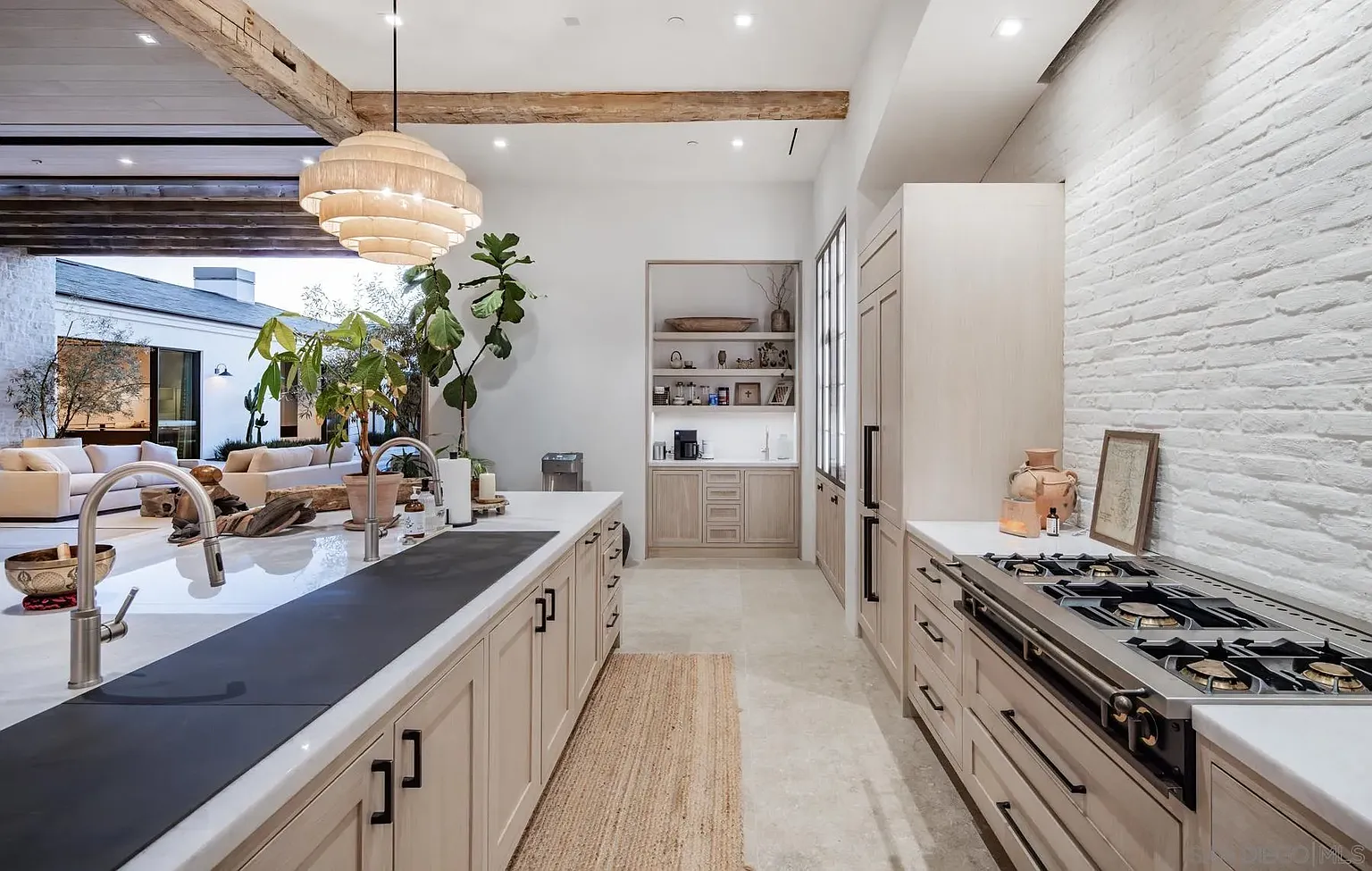 Bar seating is placed on one side of the island, while the other has a range tucked into the arched wall with tall storage concealing appliances framing both sides.
