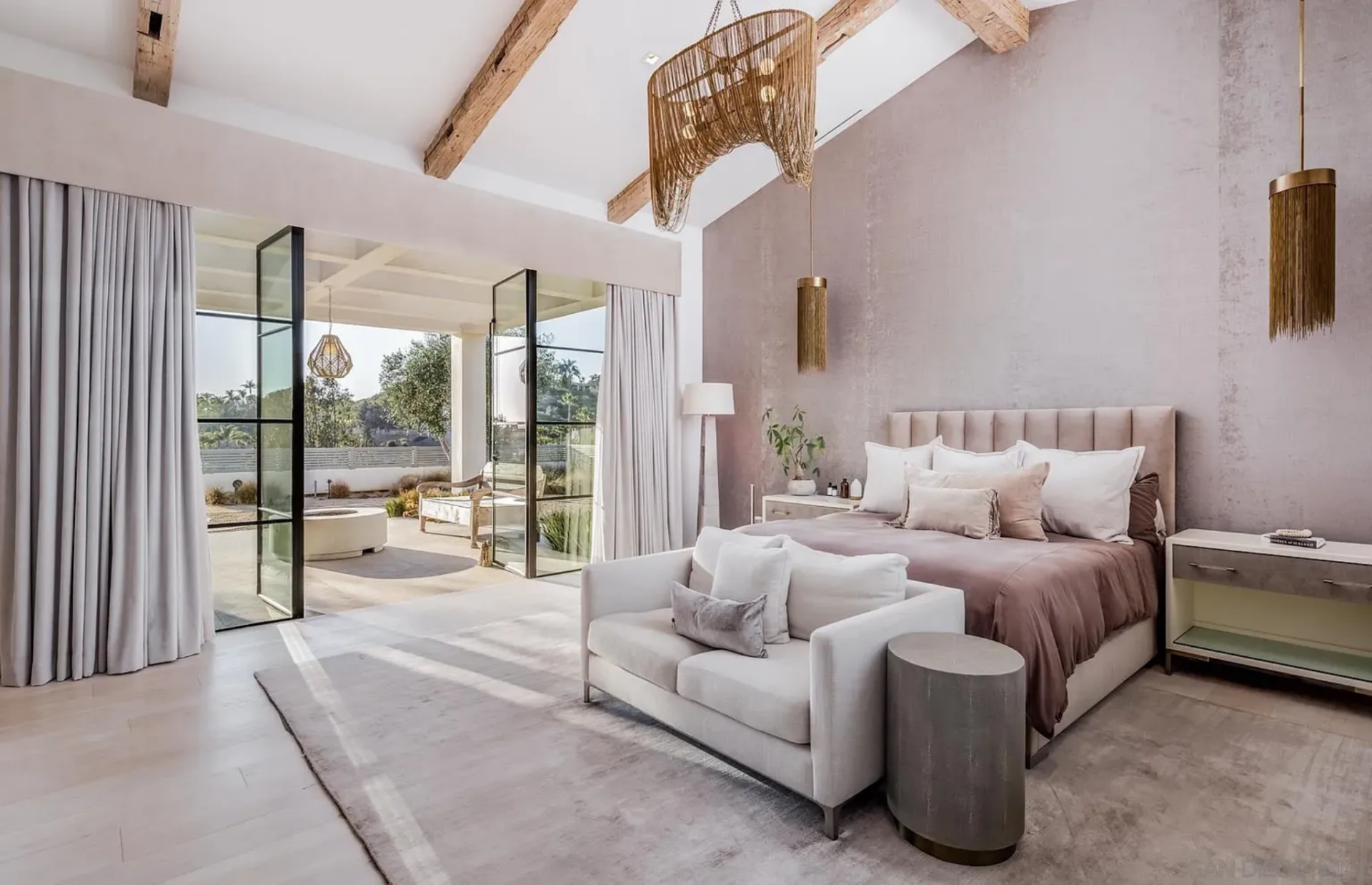 The bedroom itself keeps the palette quiet and minimal, centered on a blush-toned upholstered bed set against a textured accent wall in a similar shade. 