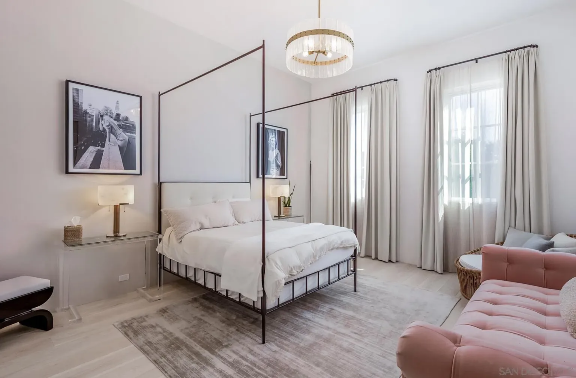 The second bedroom is a little more polished, with a dark-framed canopy bed sitting between black-and-white artwork and clear nightstands. 