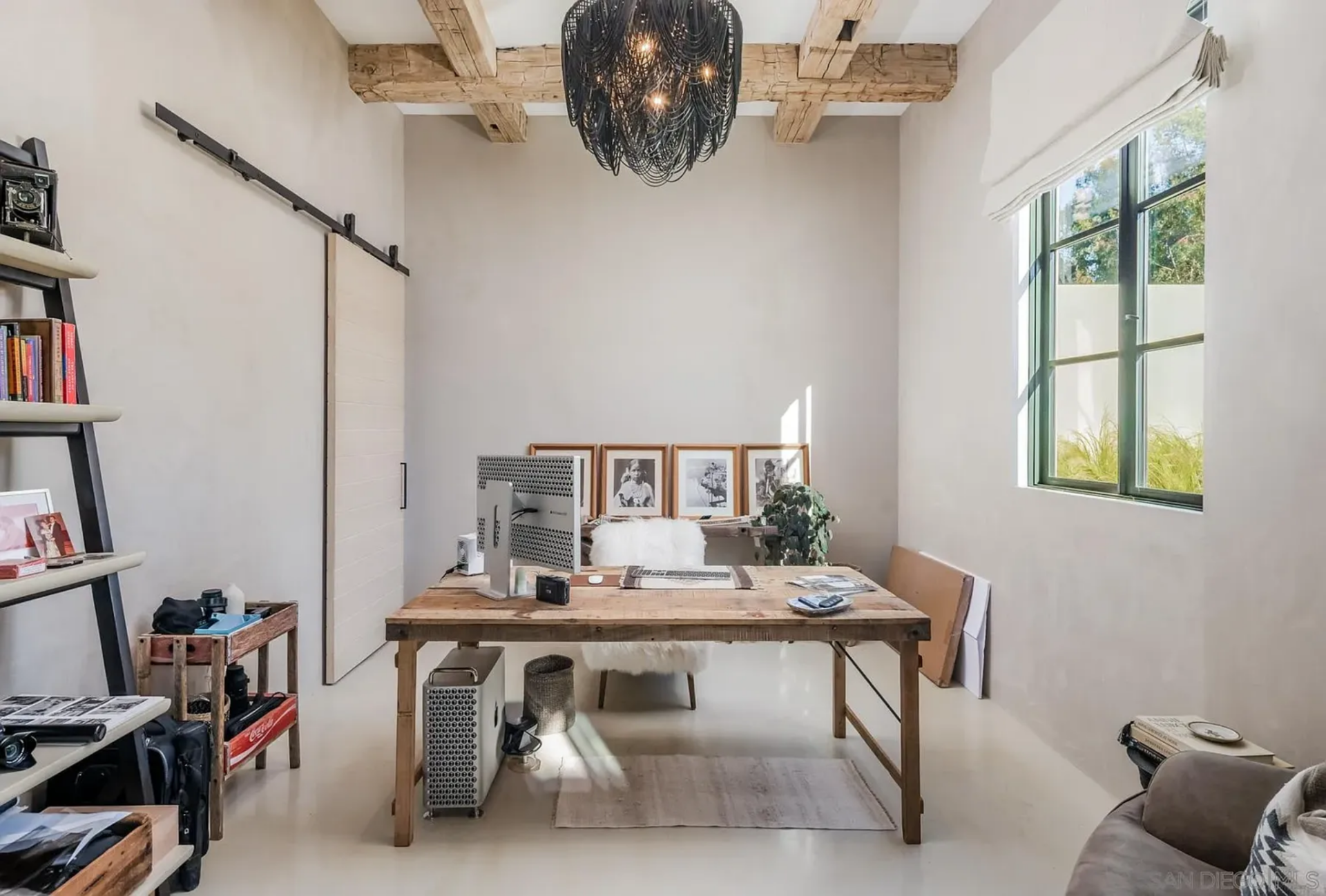 A sitting area, worktable, and large windows give it a relaxed but functional setup, while the connected office space adds a more private space for editing, organizing, and business calls.