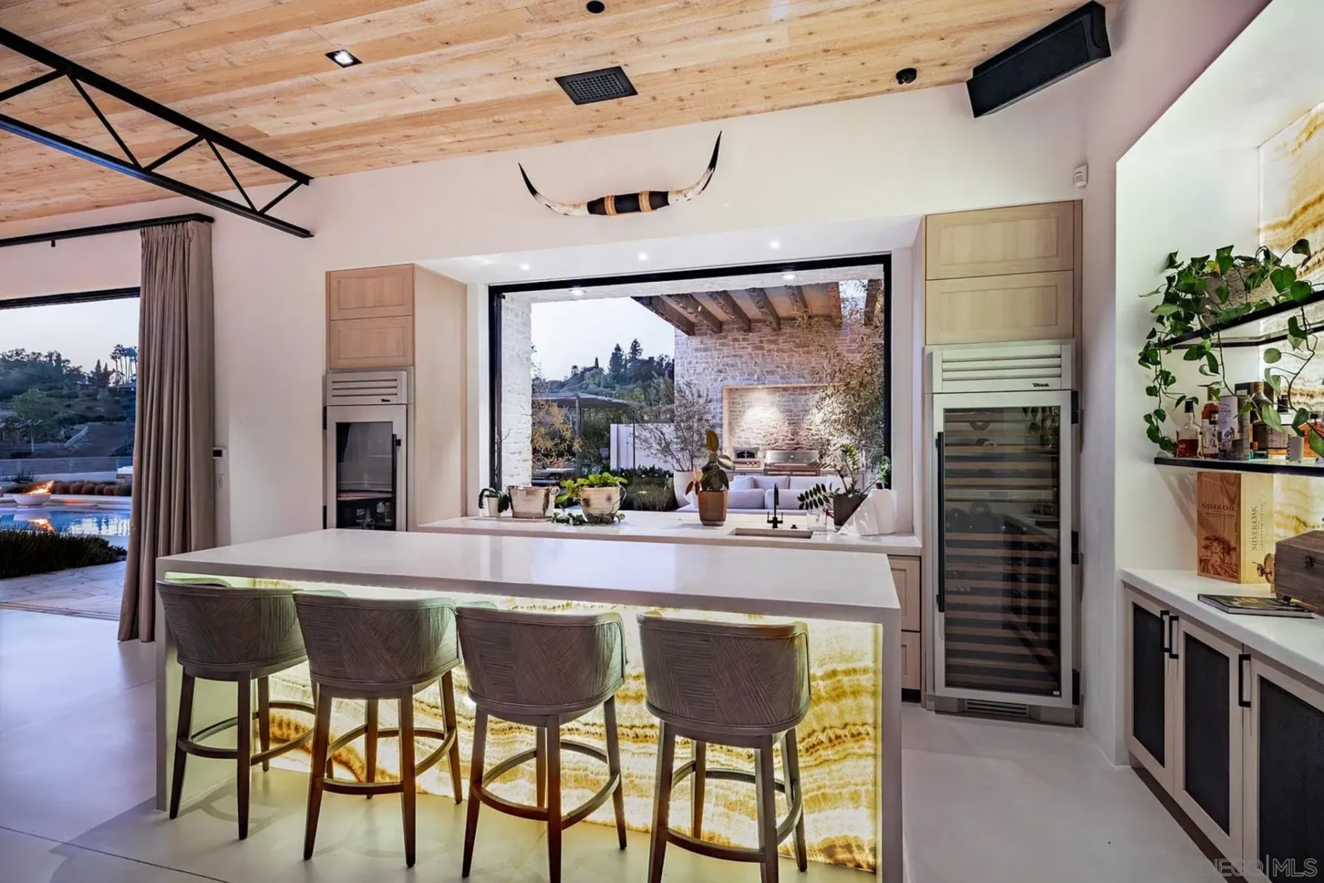 Within the game room, the bar adds another entertaining layer, built with a backlit stone-front island, undercounter refrigeration, and open shelving for bottles and glassware. 