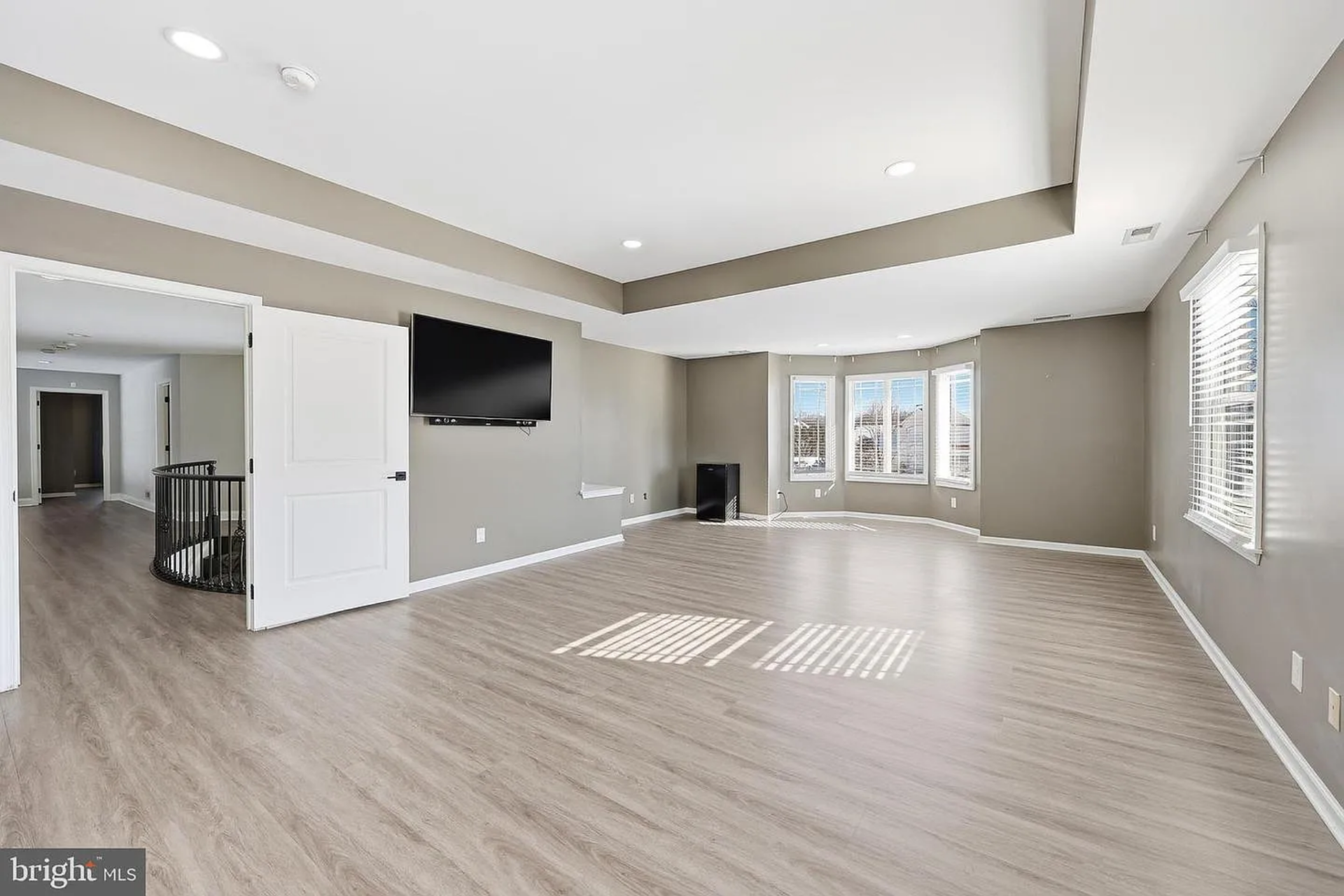 The bedroom itself is expansive, with wide-plank flooring and a tray ceiling that adds subtle dimension overhead. 