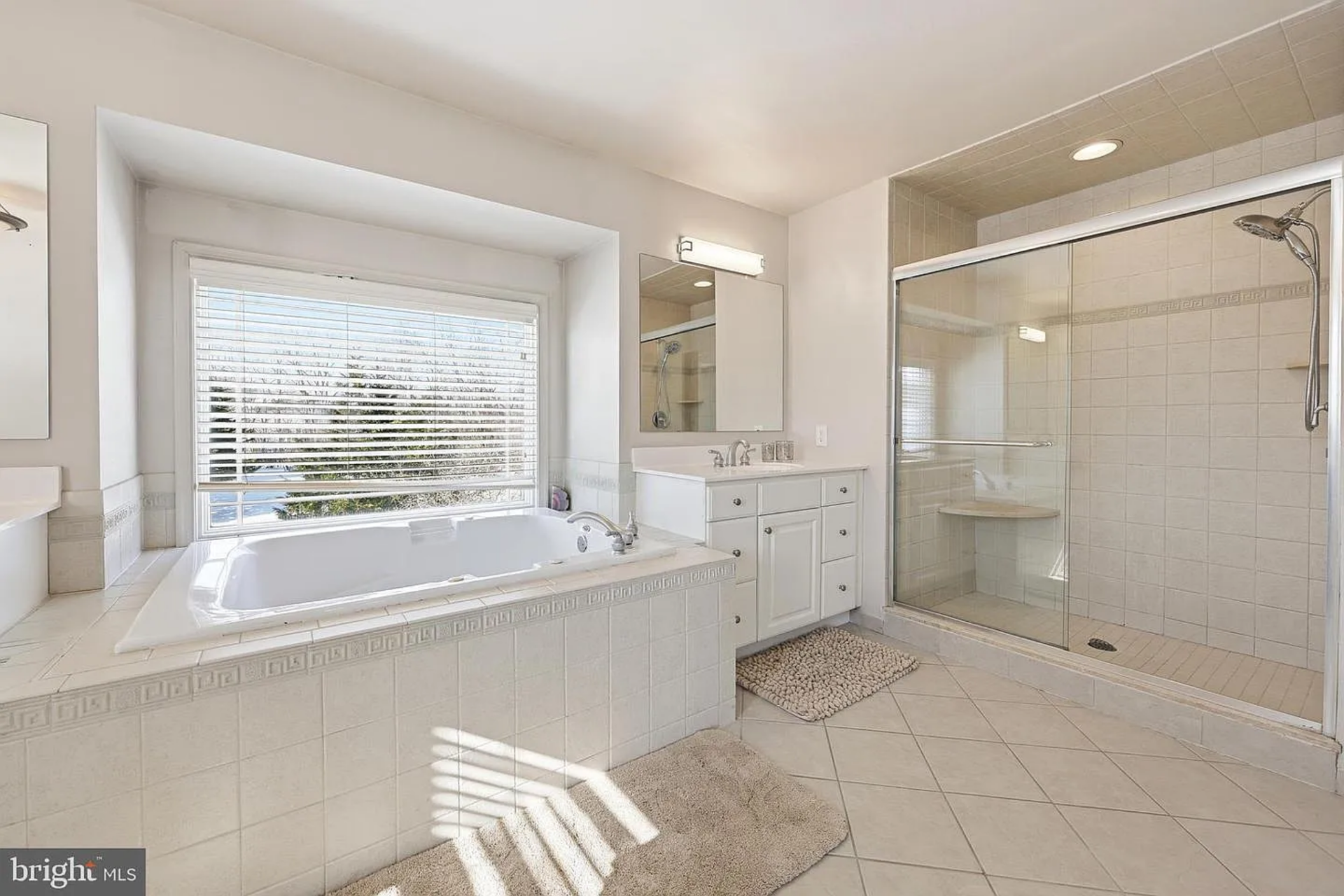 A separate glass-enclosed shower with built-in bench seating completes the space, creating a layout that balances openness with clearly defined zones for daily use.