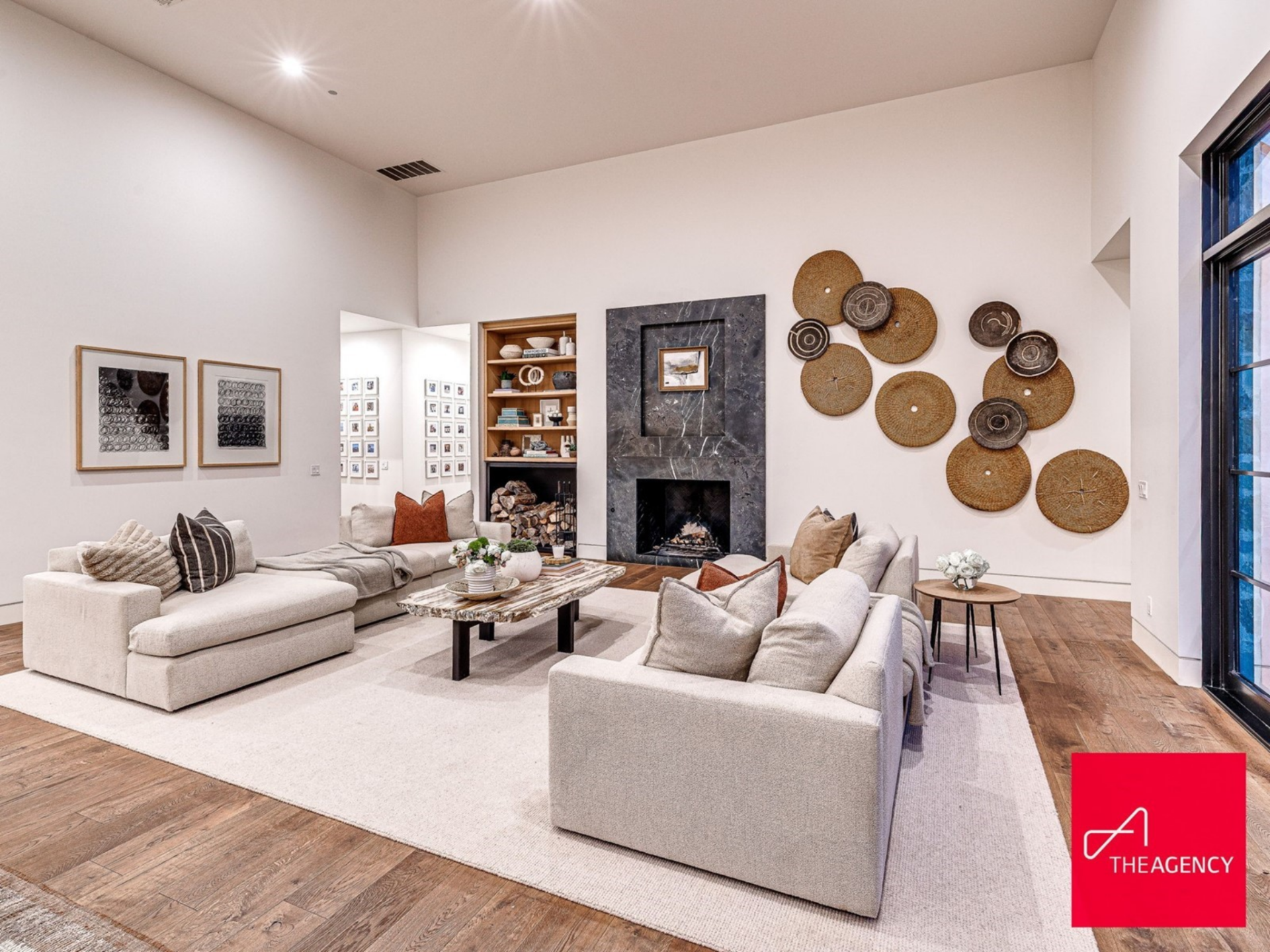 On the opposite side, the fireplace lounge, filled with two tailored sofas, creates a cozier conversation space gathered around a dark stone fireplace.