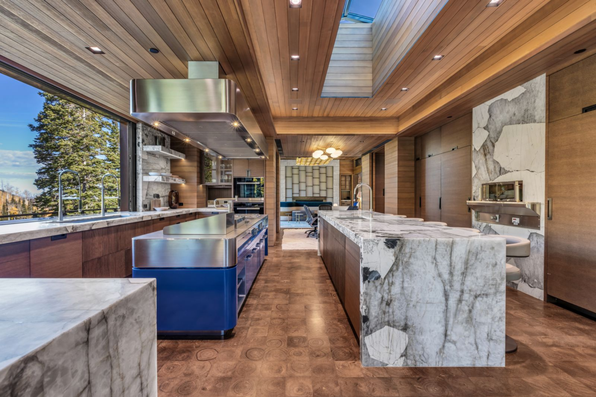 At the heart of the kitchen, a dramatic marble waterfall island stretches nearly the length of the room, its thick veining creating a sculptural focal point.