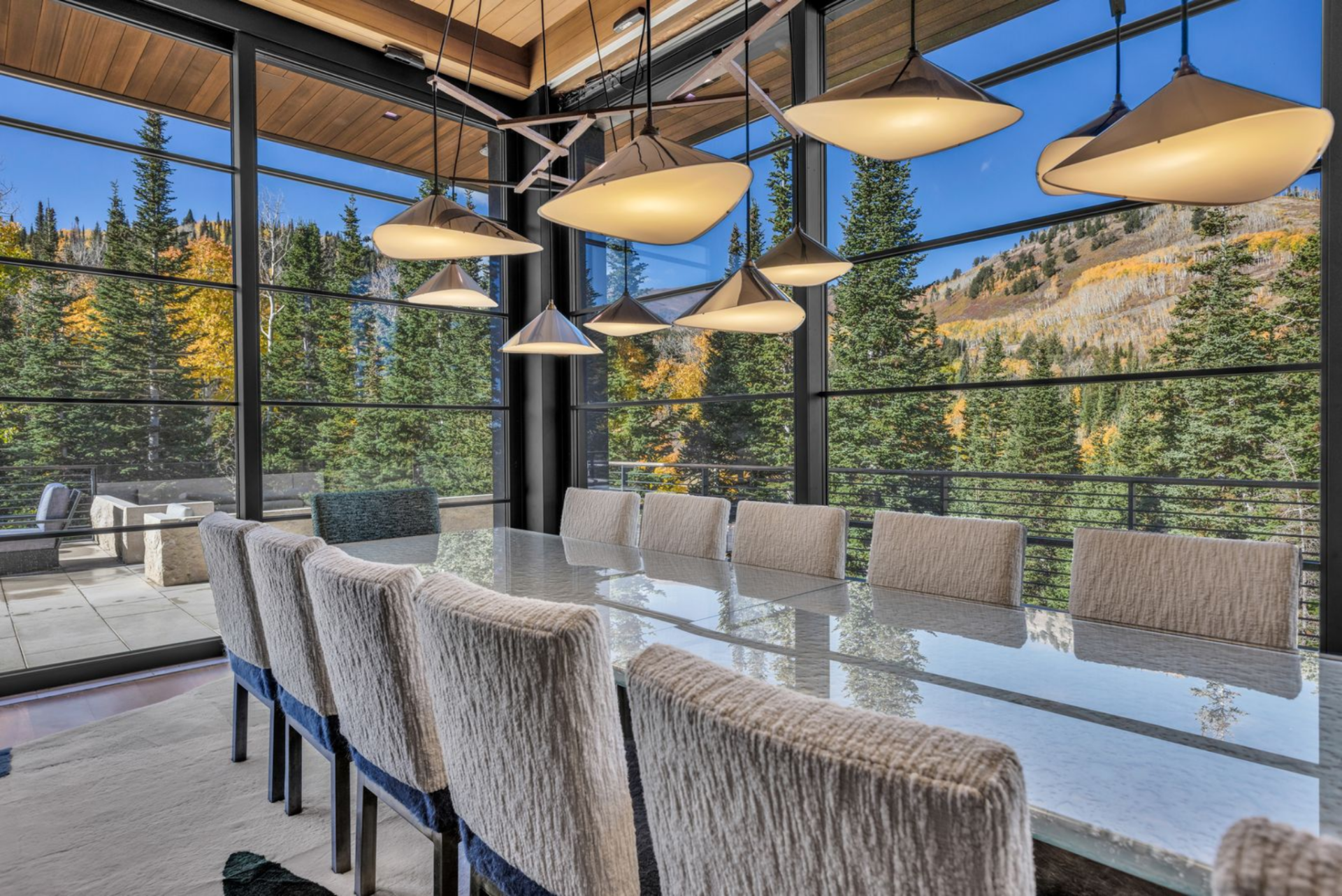 Just beyond the kitchen, the space opens into a dining area where the table sits directly against a window wall, positioned to take full advantage of the mountain backdrop.