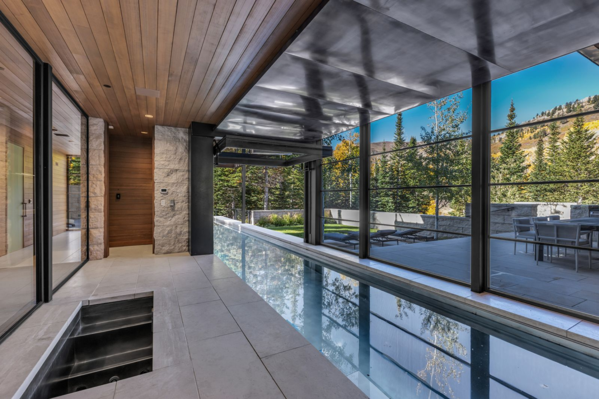 Right behind the gym, a striking 60-foot stainless steel lap pool runs alongside the home, linking interior corridors with the landscaped exterior.