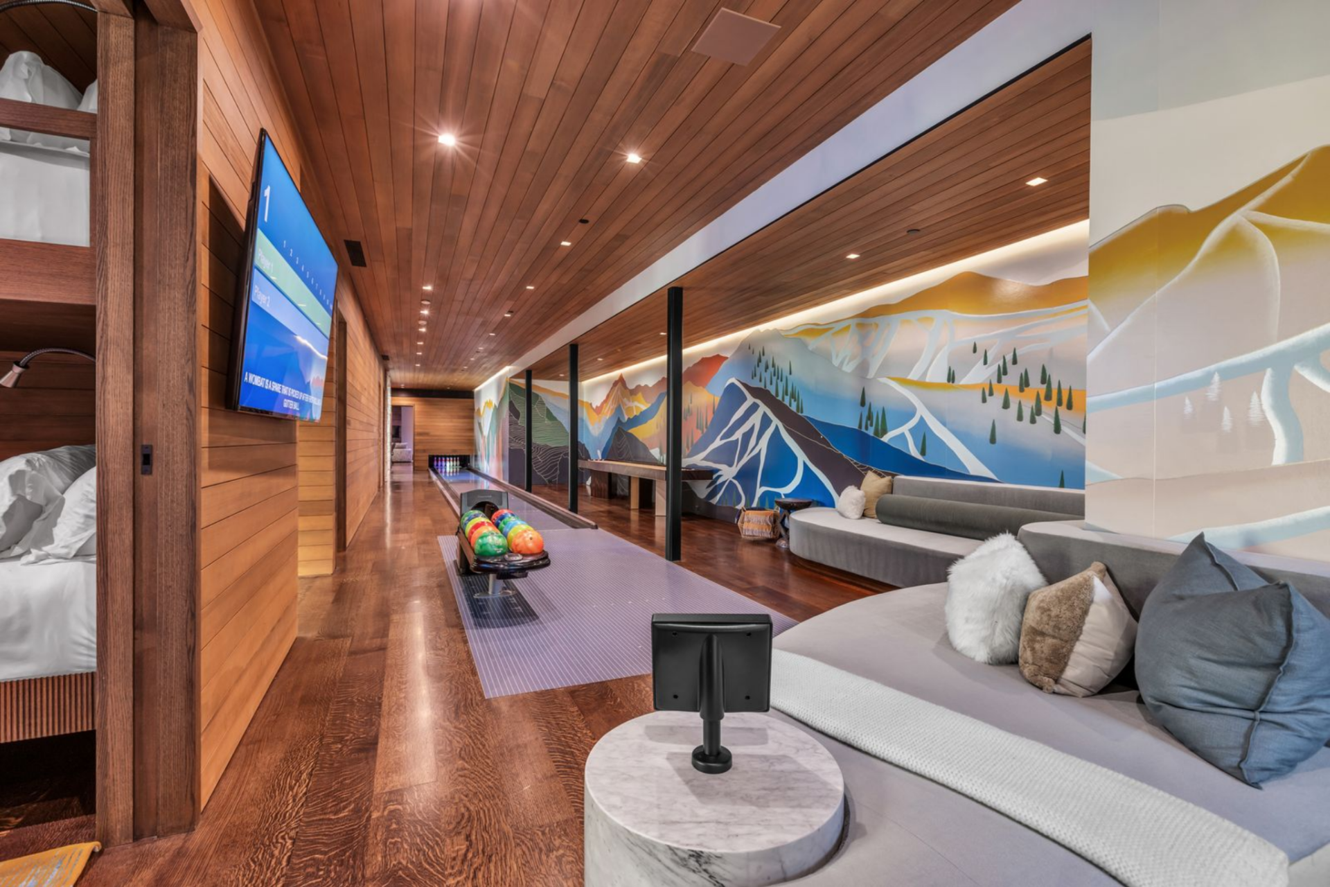 The custom bowling alley is lined with rich wood finishes and a colorful mountain mural that stretches the length of the lane.