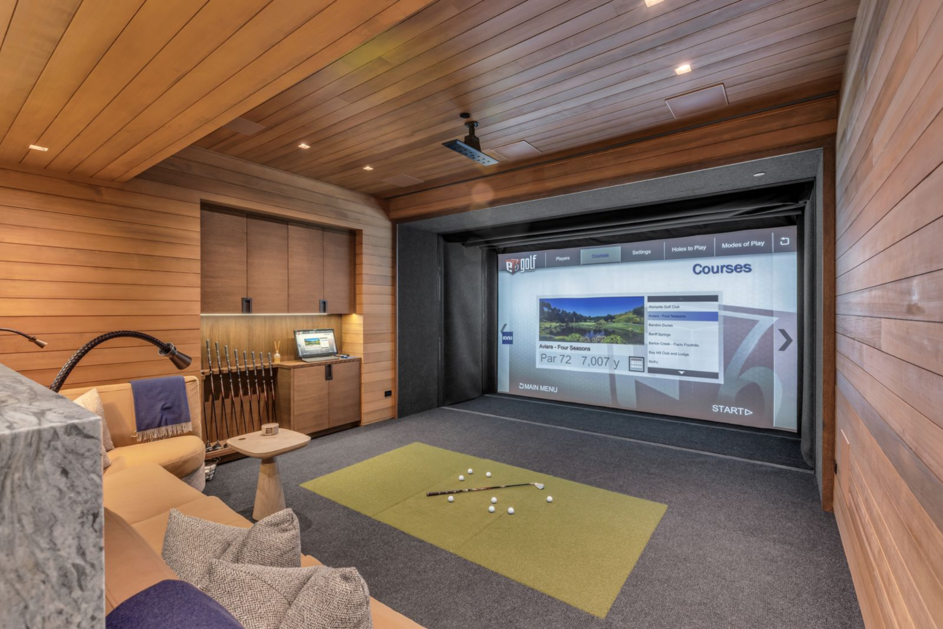 A dedicated golf simulator room features a full projection screen, built-in cabinetry for storing clubs, and lounge seating for spectators.