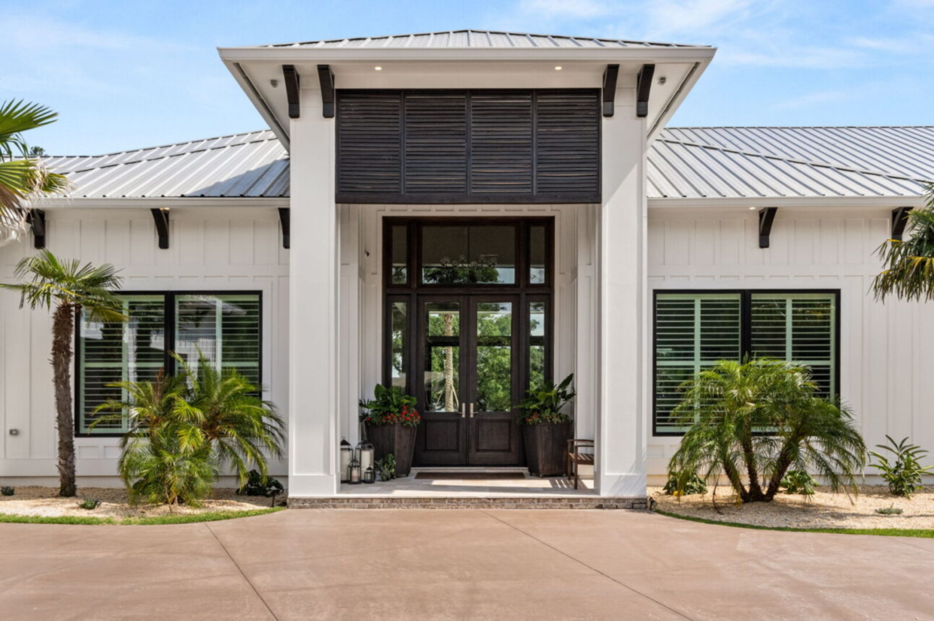 Walking closer to the entrance, the architecture becomes more focused around the central portico. Tall white columns frame a covered entryway, drawing attention to the oversized glass double doors.