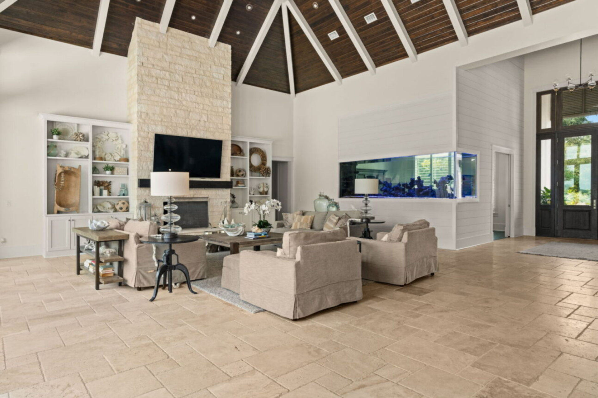 Dark wood paneling lines the ceiling between white beams that radiate outward, drawing the eye upward and adding contrast to the otherwise bright, coastal-inspired interior.
